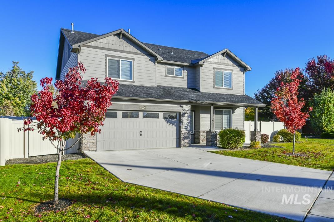 Craftsman inspired home with stone siding, a shingled roof, driveway, and a garage