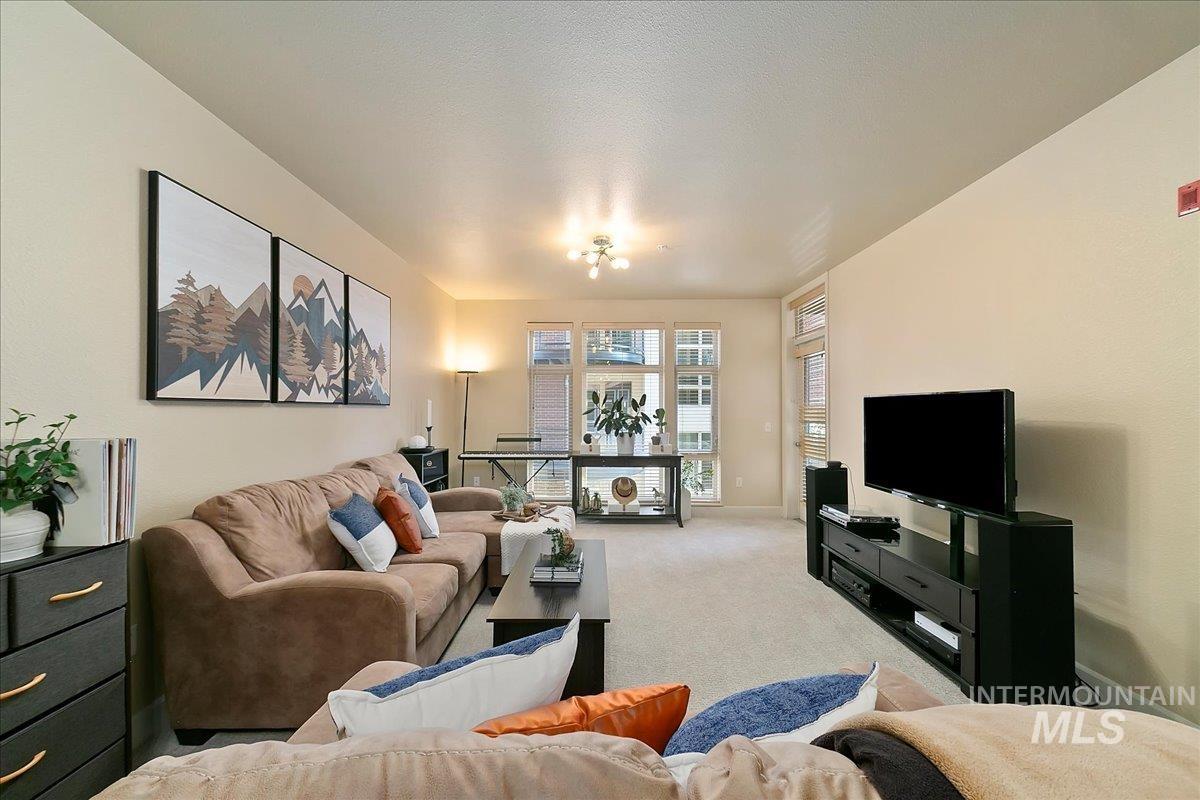 Living area featuring light colored carpet and baseboards