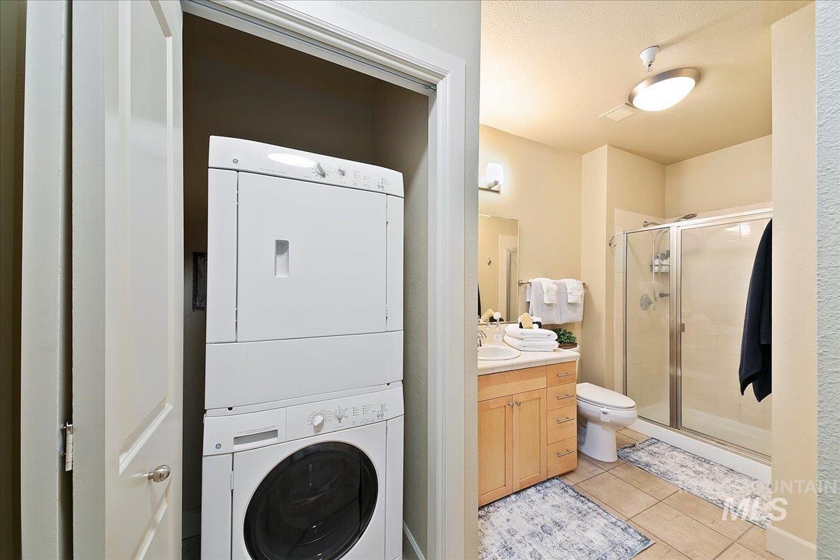 Bathroom with vanity, a stall shower, stacked washer and dryer, and light tile patterned flooring