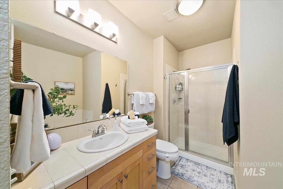 Bathroom with vanity, a stall shower, and light tile patterned flooring