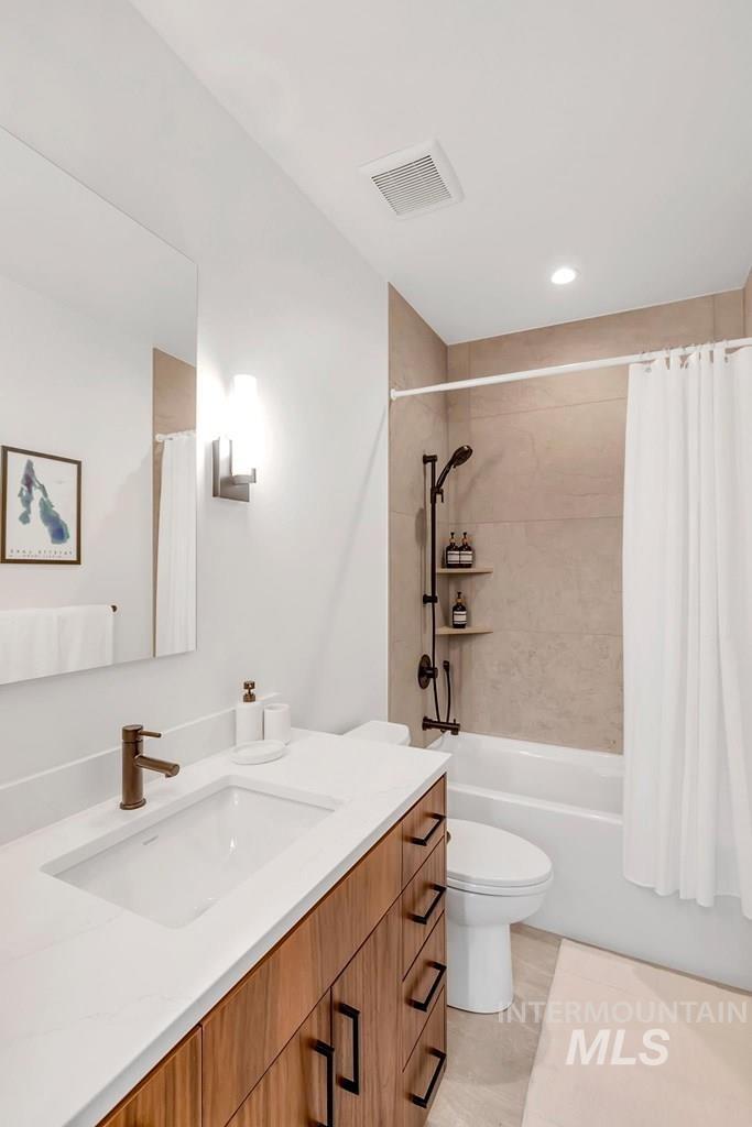 Bathroom featuring vanity, shower / bathtub combination with curtain, recessed lighting, and light tile patterned floors