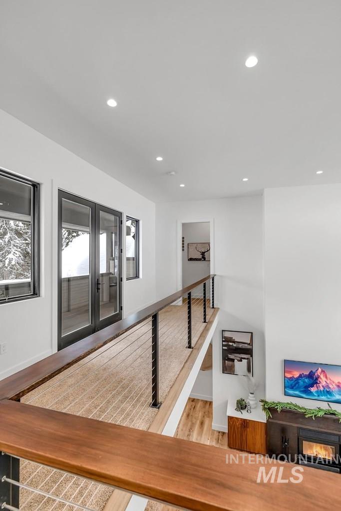 Hallway featuring wood finished floors, recessed lighting, and an upstairs landing