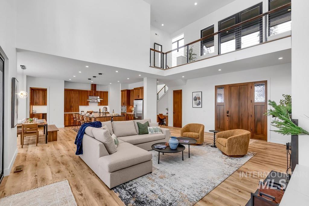 Living room featuring recessed lighting, plenty of natural light, a high ceiling, light wood-style floors, and stairs