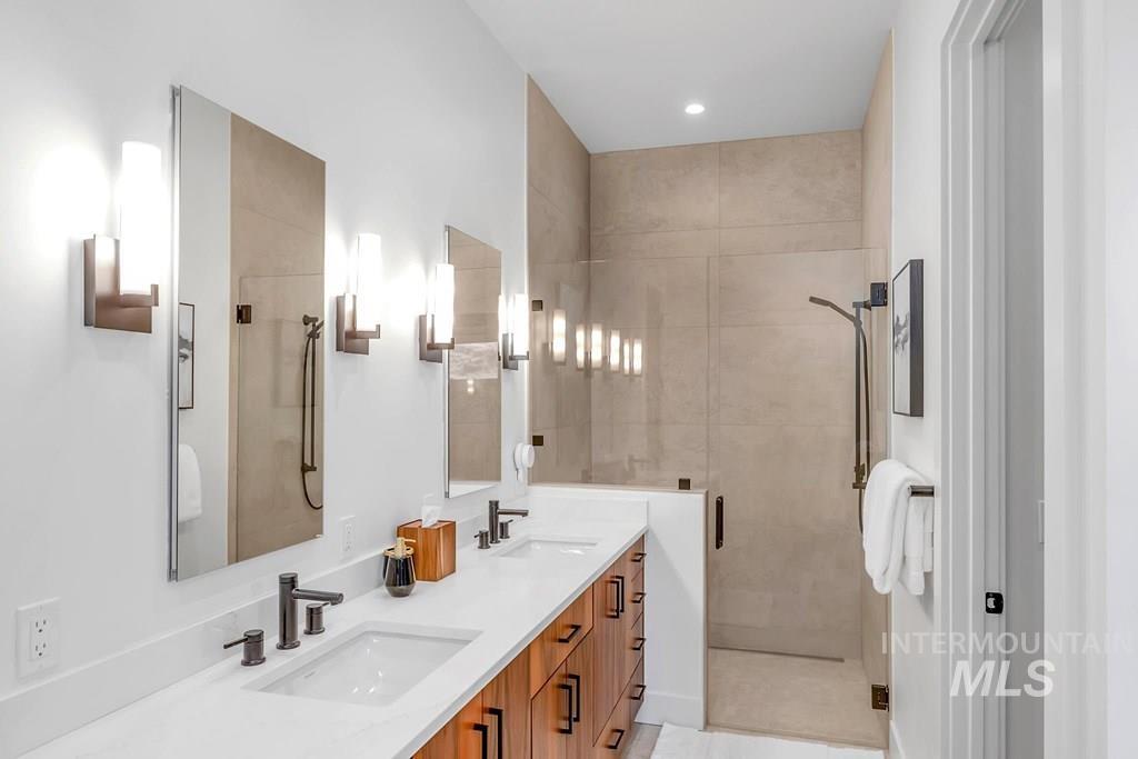 Full bathroom featuring a stall shower, double vanity, and recessed lighting