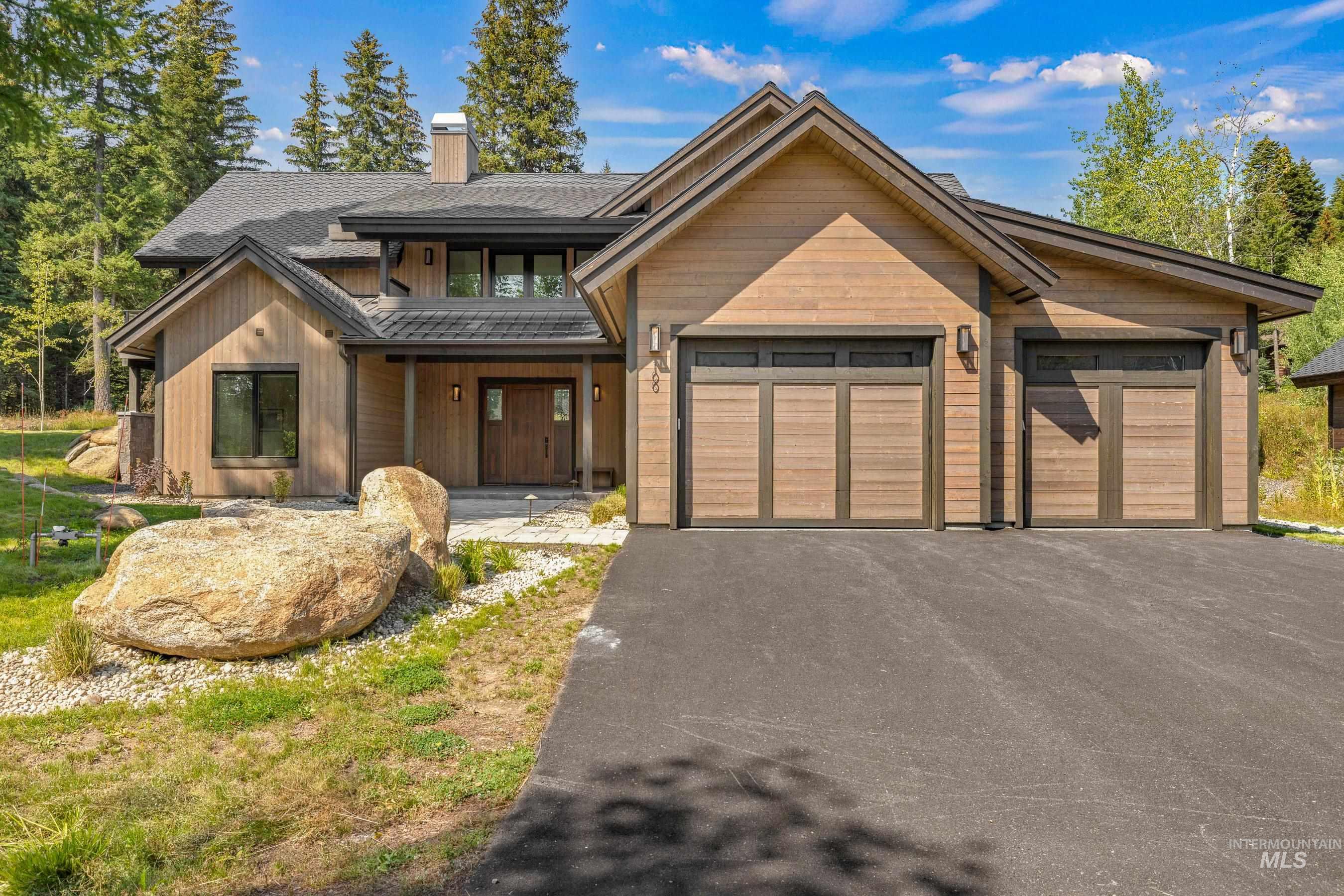 View of front of home featuring asphalt driveway, covered porch, a garage, a chimney, and board and batten siding