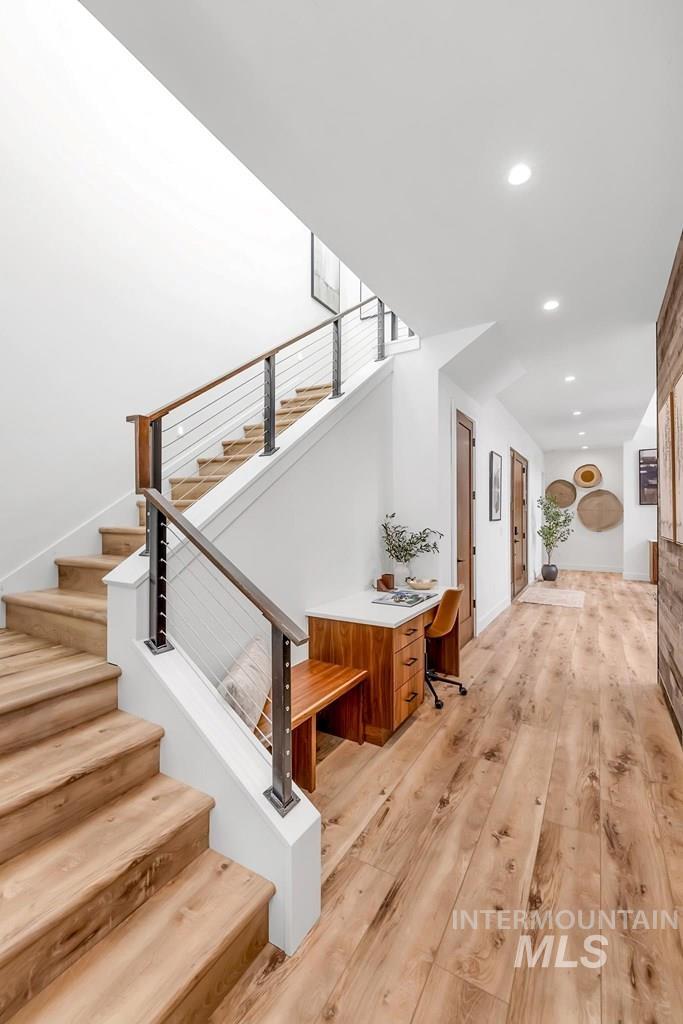 Staircase with wood finished floors and recessed lighting