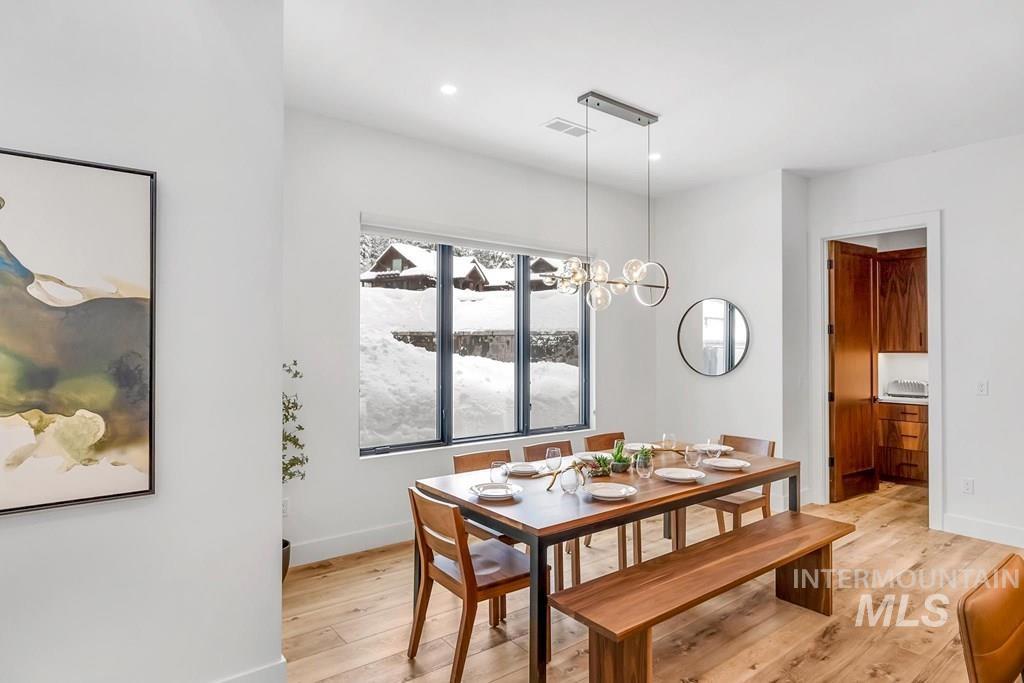 Dining area with light wood finished floors, a chandelier, and recessed lighting