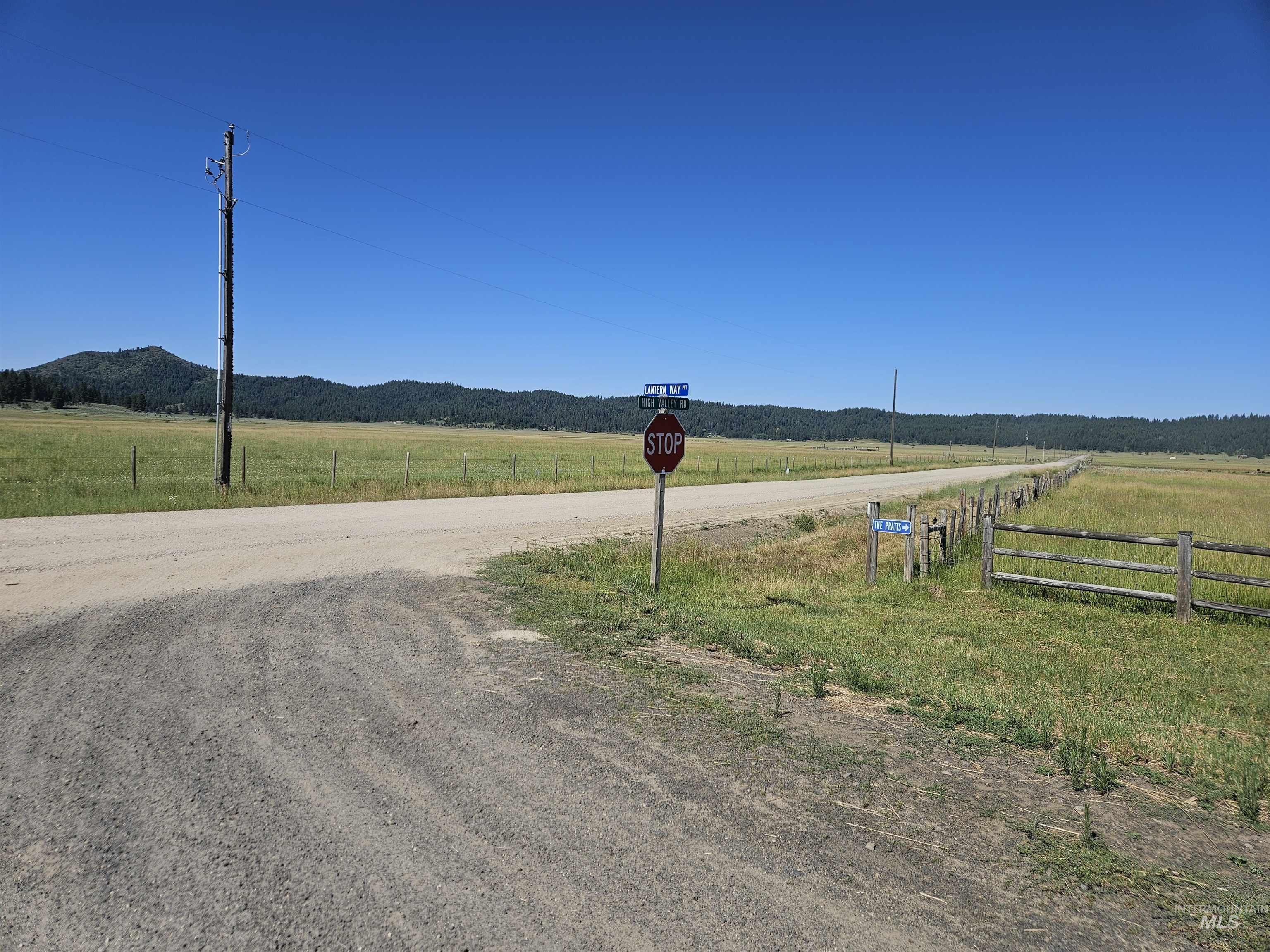View of dirt / gravel road featuring a rural view, traffic signs, and a mountain view