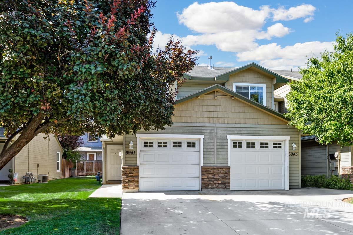 View of front of house featuring driveway, stone siding, a front yard, and a garage