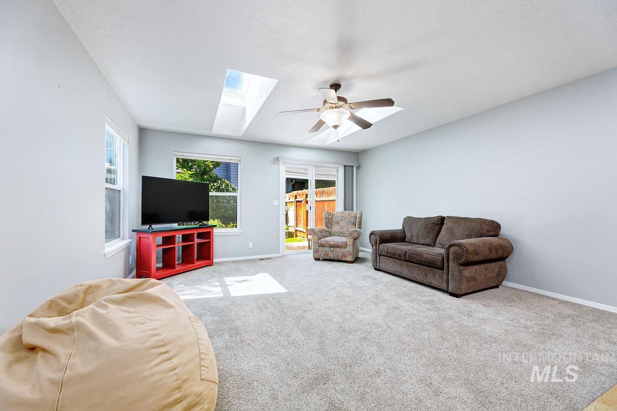 Living room featuring a skylight, ceiling fan, and carpet flooring