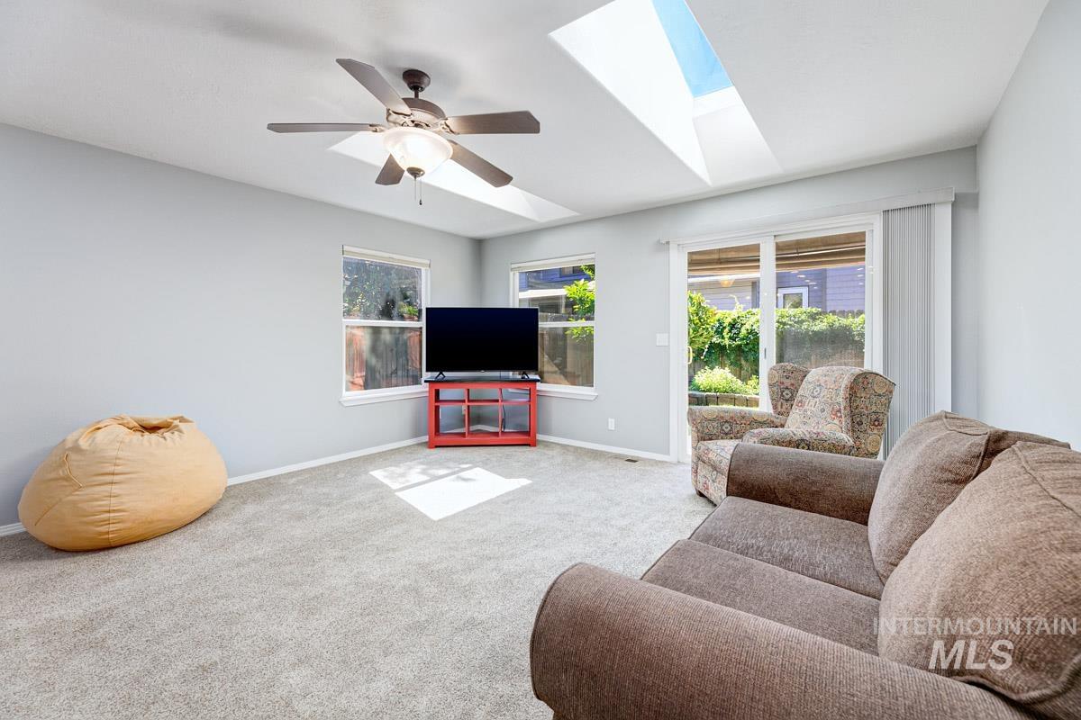 Living room featuring a skylight, carpet, and a ceiling fan
