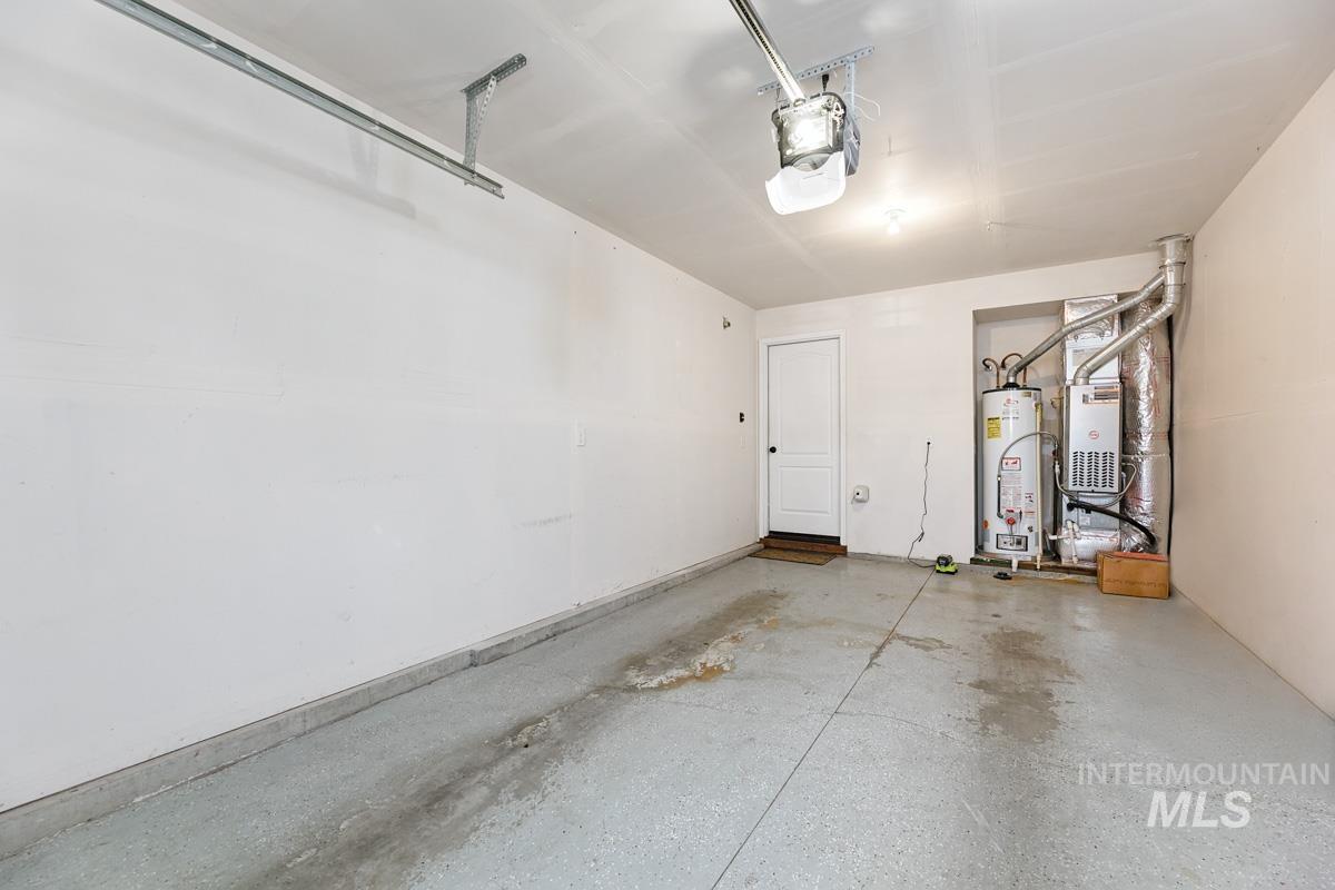 Garage featuring gas water heater, heating unit, and a garage door opener
