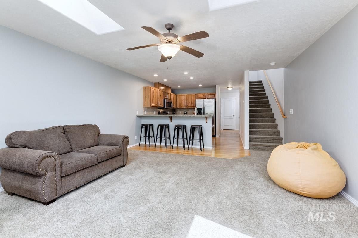 Living area featuring light carpet, stairway, a ceiling fan, a skylight, and recessed lighting