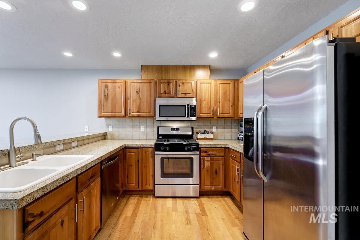Kitchen with stainless steel appliances, light wood-style floors, brown cabinetry, and recessed lighting