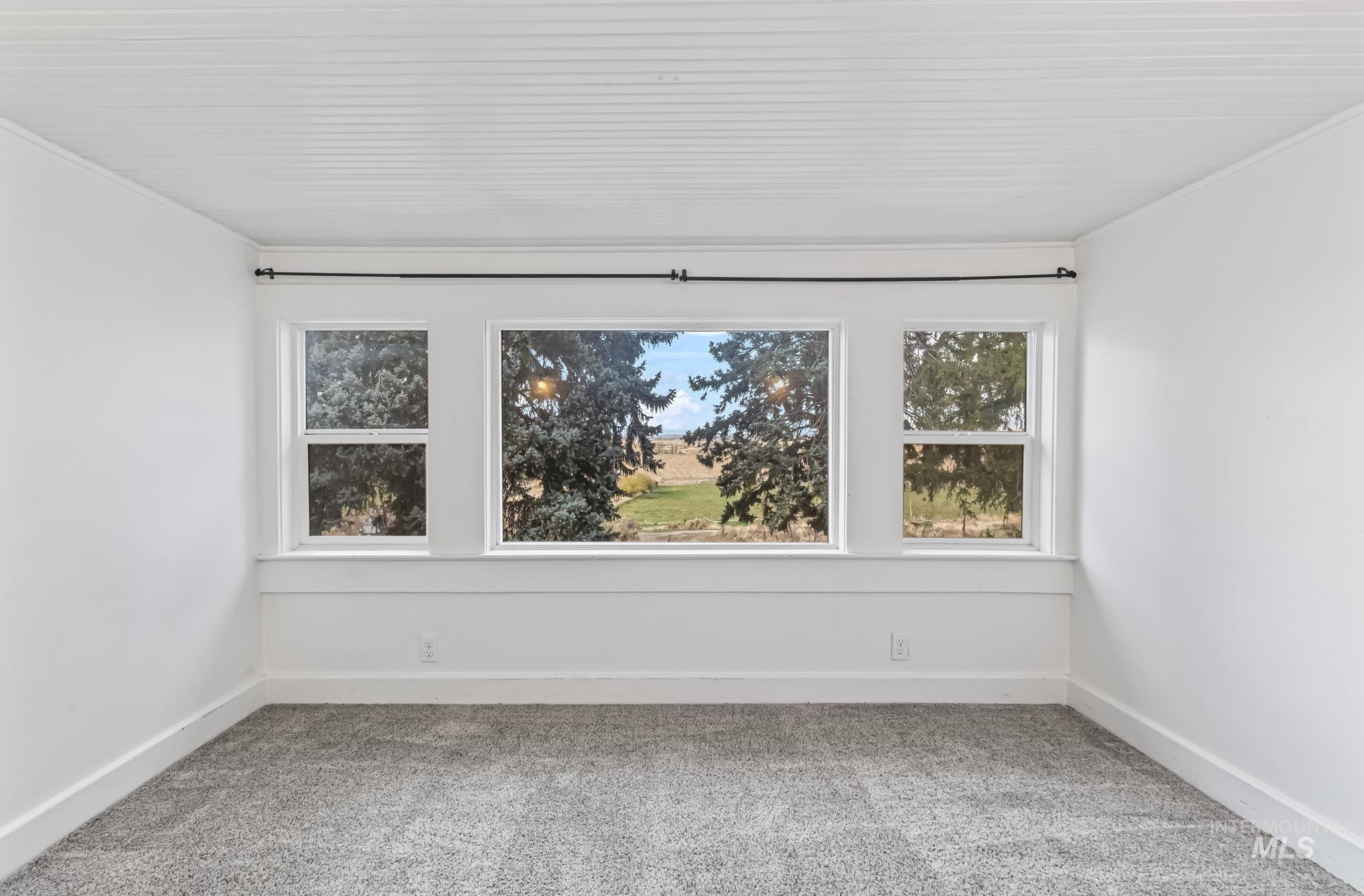 Empty room with light colored carpet and baseboards