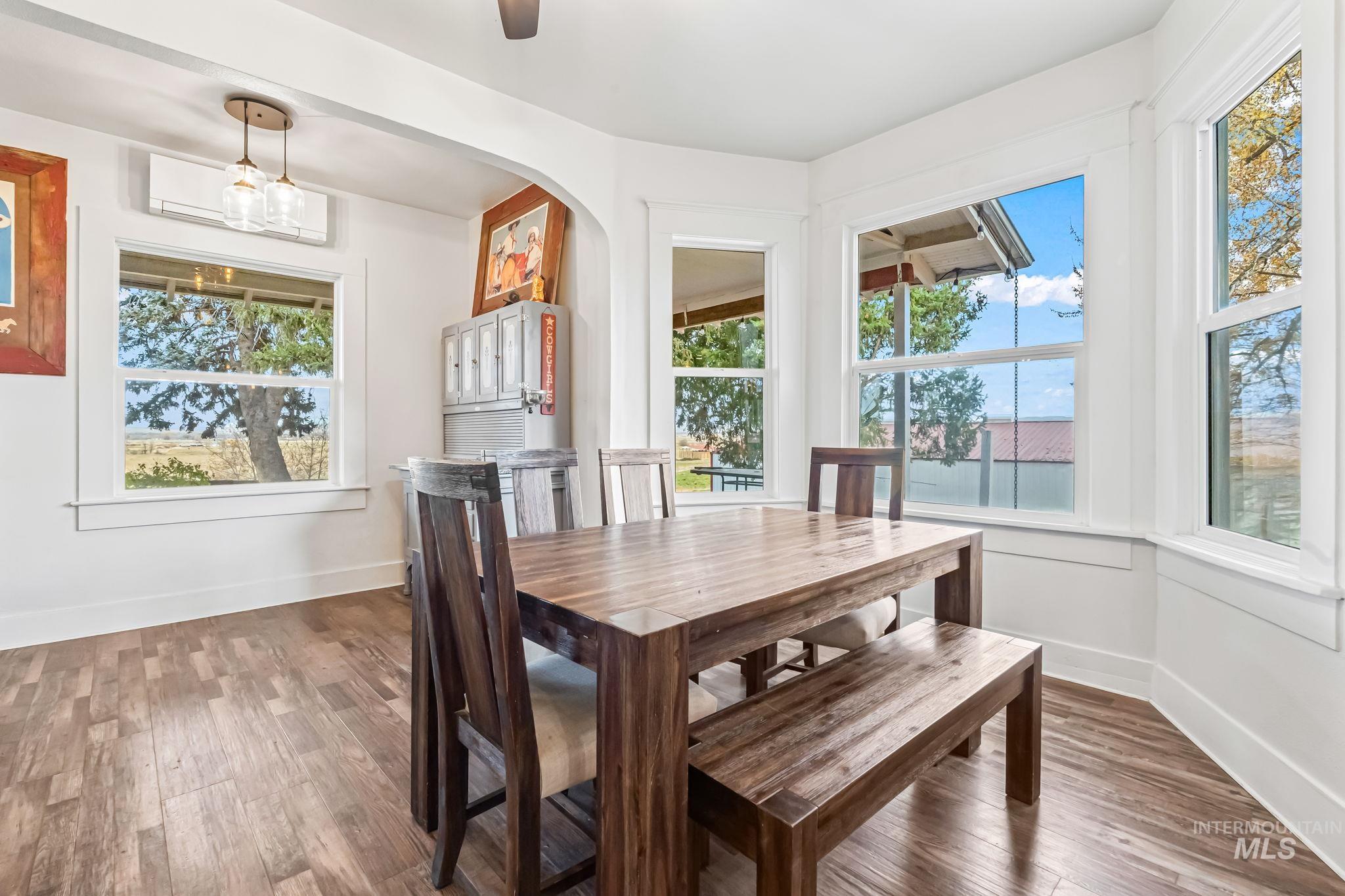 Dining area featuring wood finished floors, an AC wall unit, and arched walkways