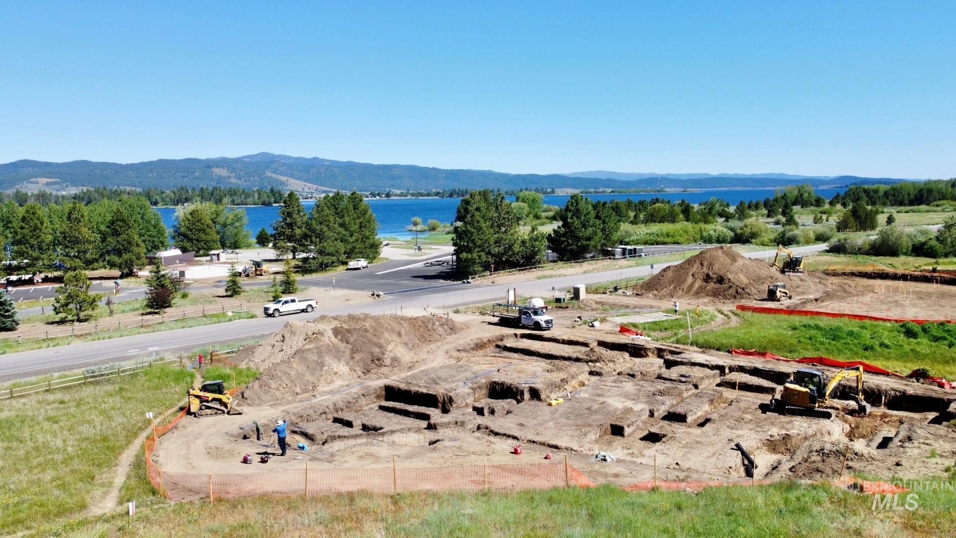 Excavated site featuring foundational trenches and a prominent water body in the background