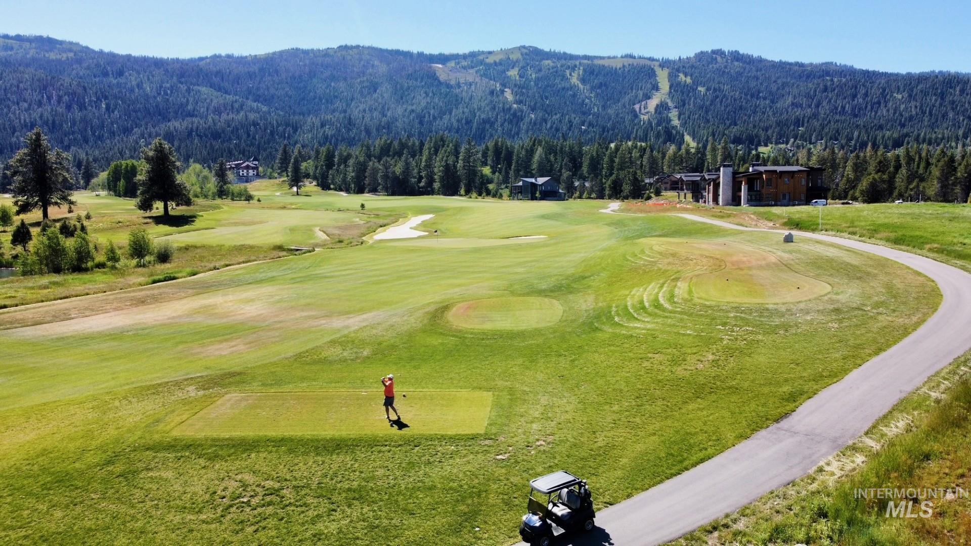 Expansive golf course featuring manicured greens and a paved cart path