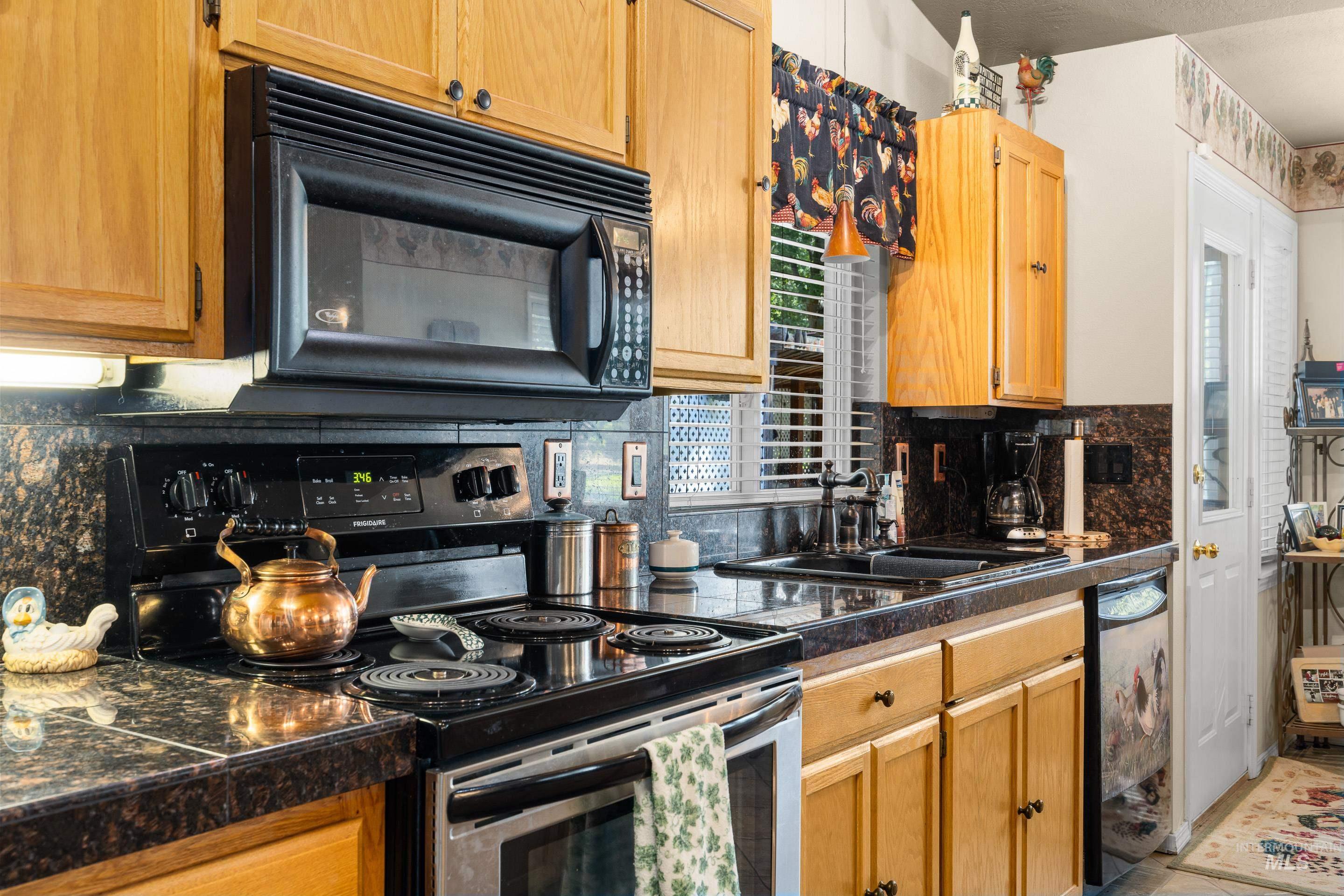Kitchen featuring black appliances, tile countertops, and tasteful backsplash