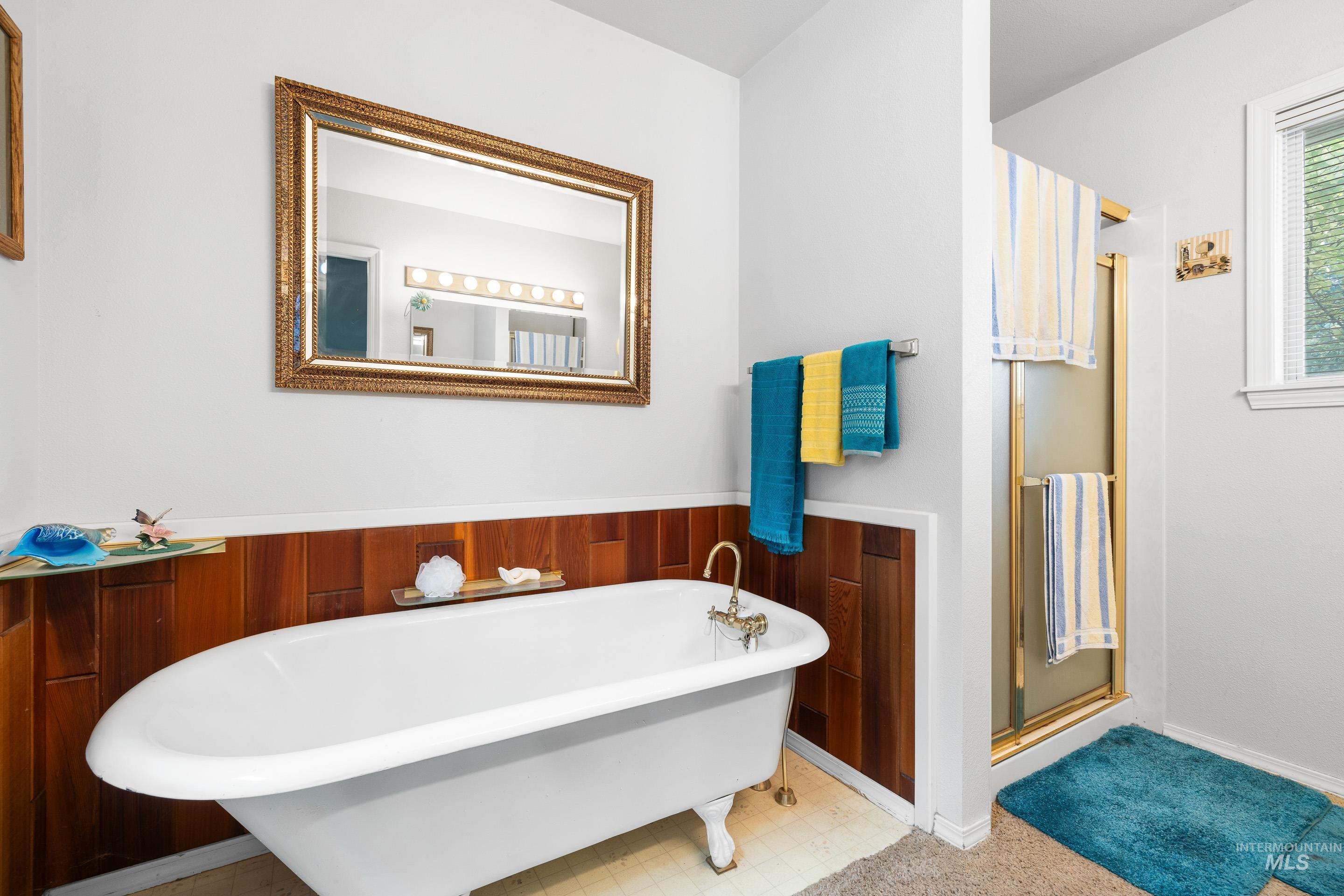 Bathroom with a freestanding tub, a stall shower, a wainscoted wall, and wood walls