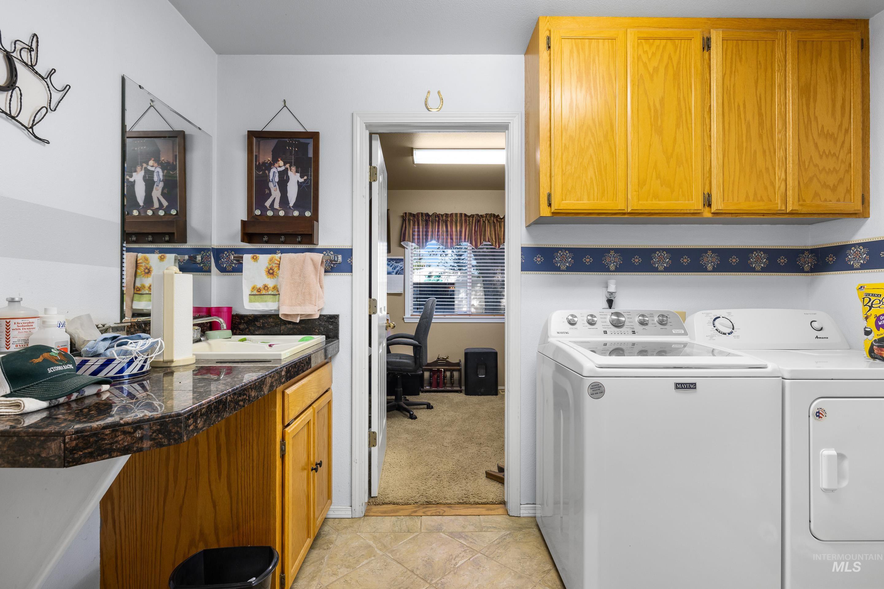 Laundry area with cabinet space, washing machine and dryer, a desk, light carpet, and light tile patterned flooring