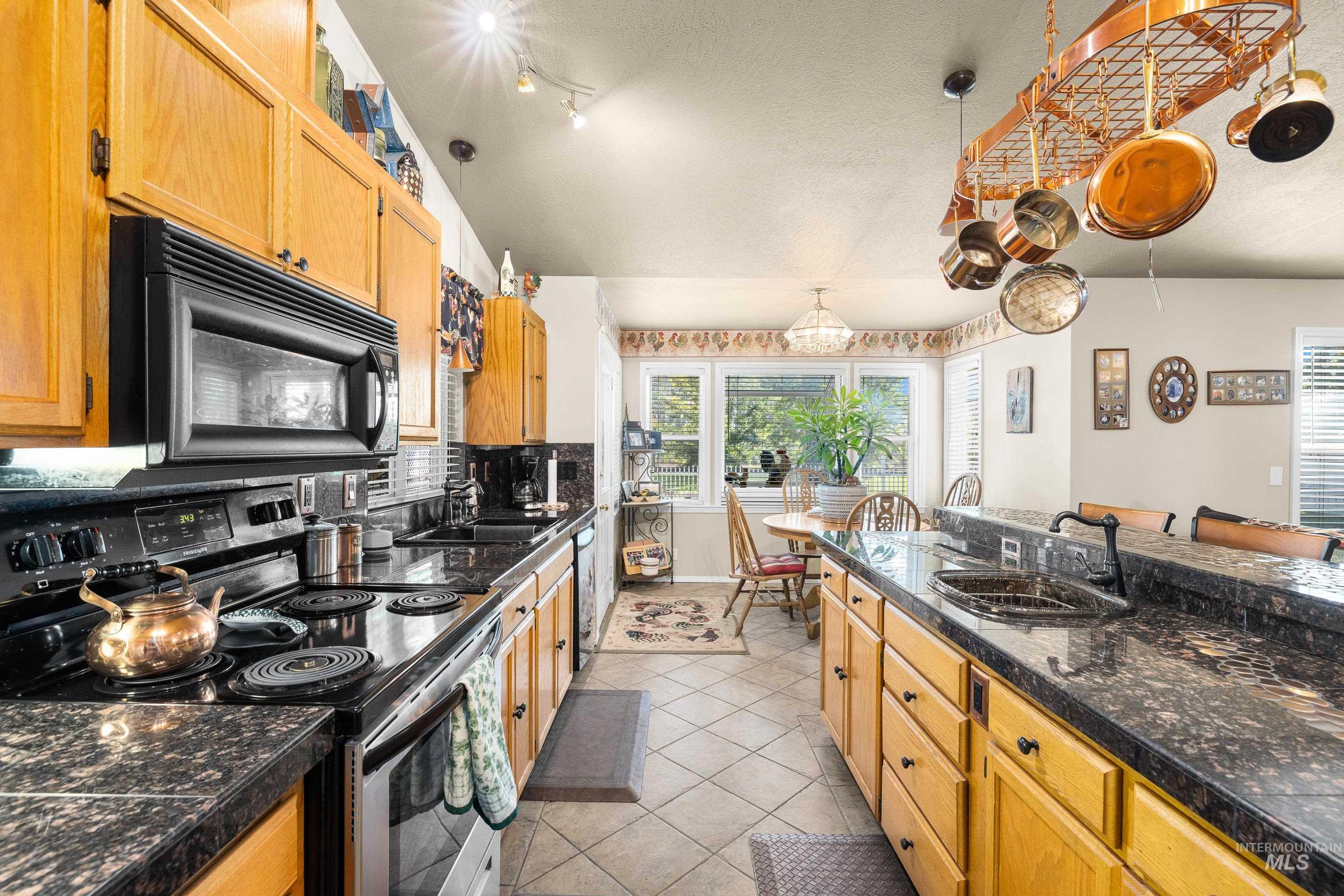 Kitchen featuring black appliances, light tile patterned floors, tasteful backsplash, and a textured ceiling