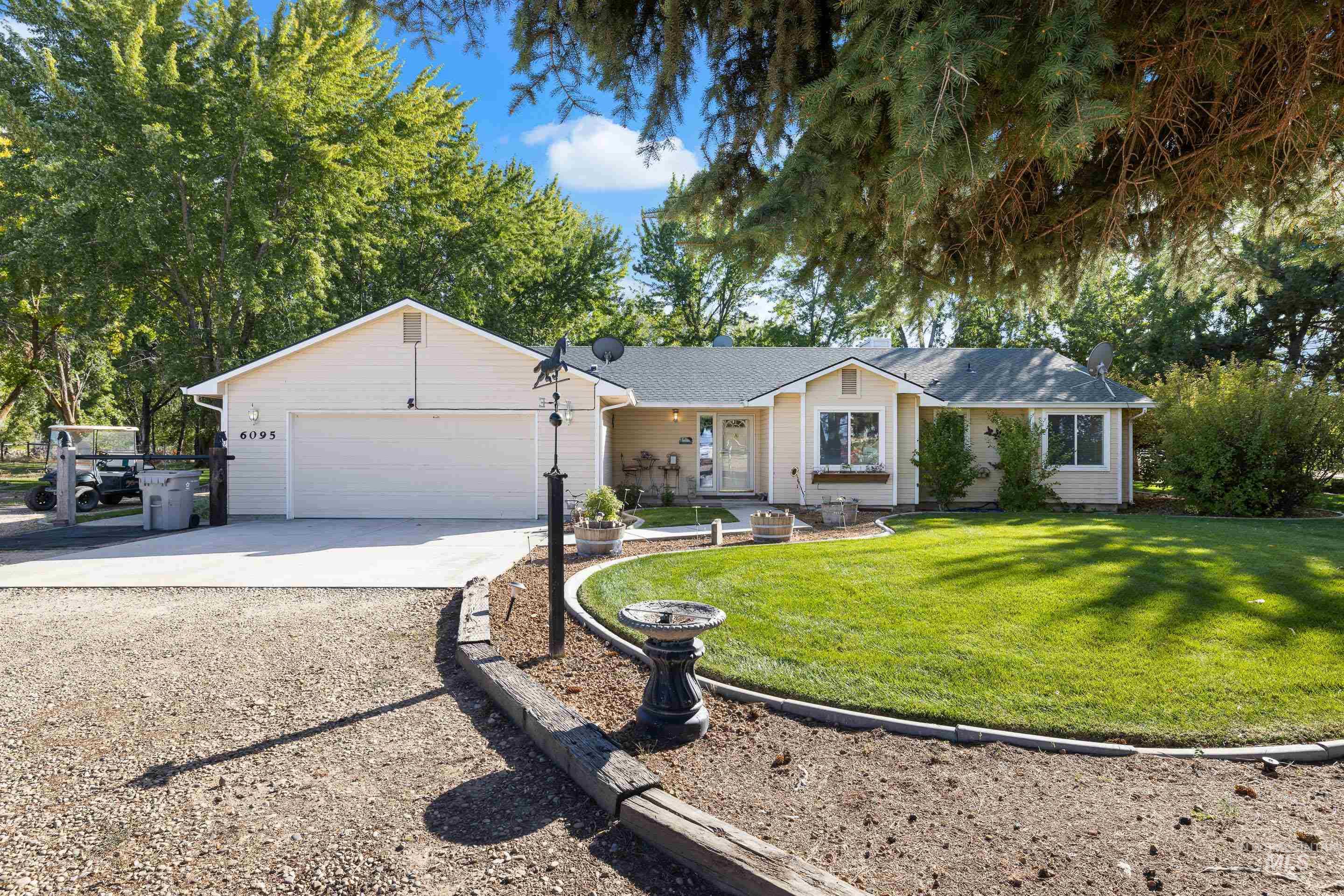 Ranch-style house featuring driveway, a front yard, an attached garage, and a porch