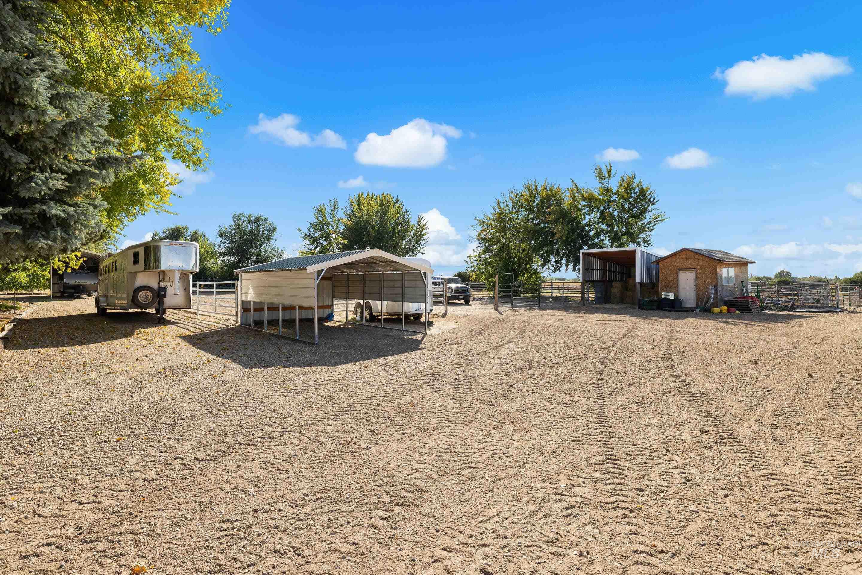 View of yard featuring an outbuilding, a carport, dirt driveway, and a pole building