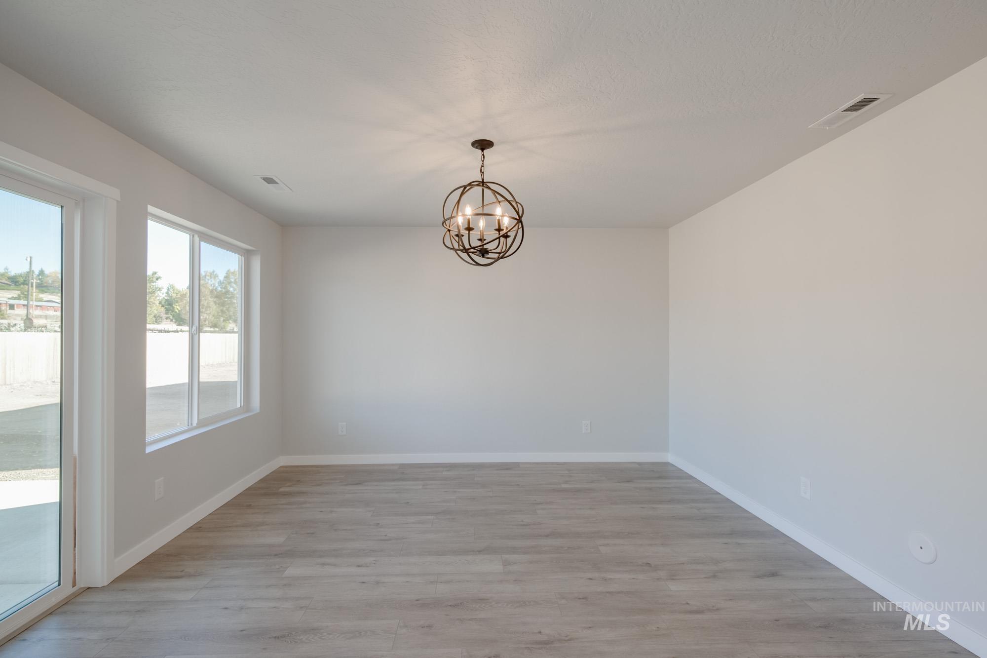 Unfurnished dining area featuring light wood-type flooring and a chandelier