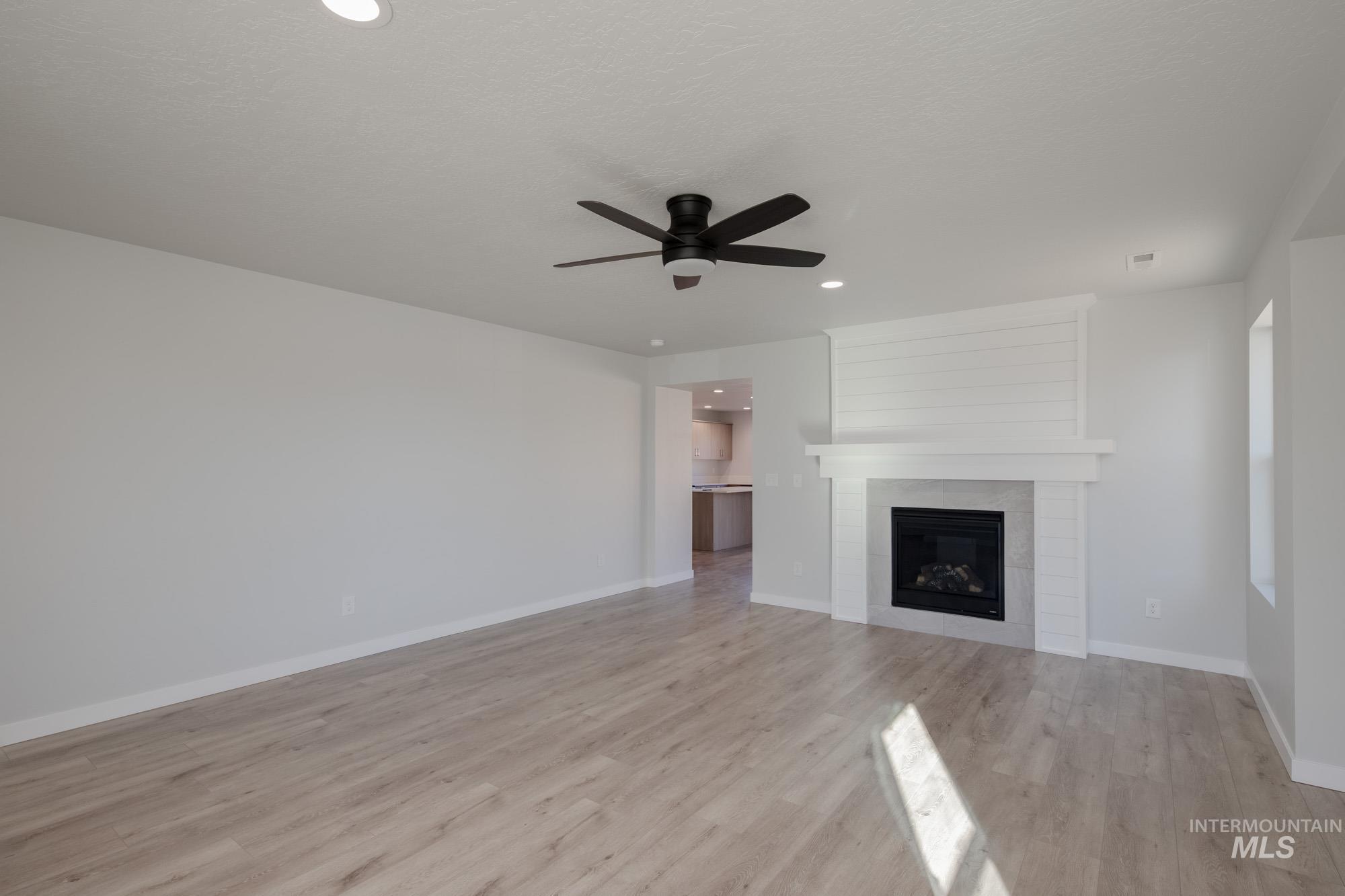 Unfurnished living room featuring a fireplace, light wood finished floors, recessed lighting, and ceiling fan
