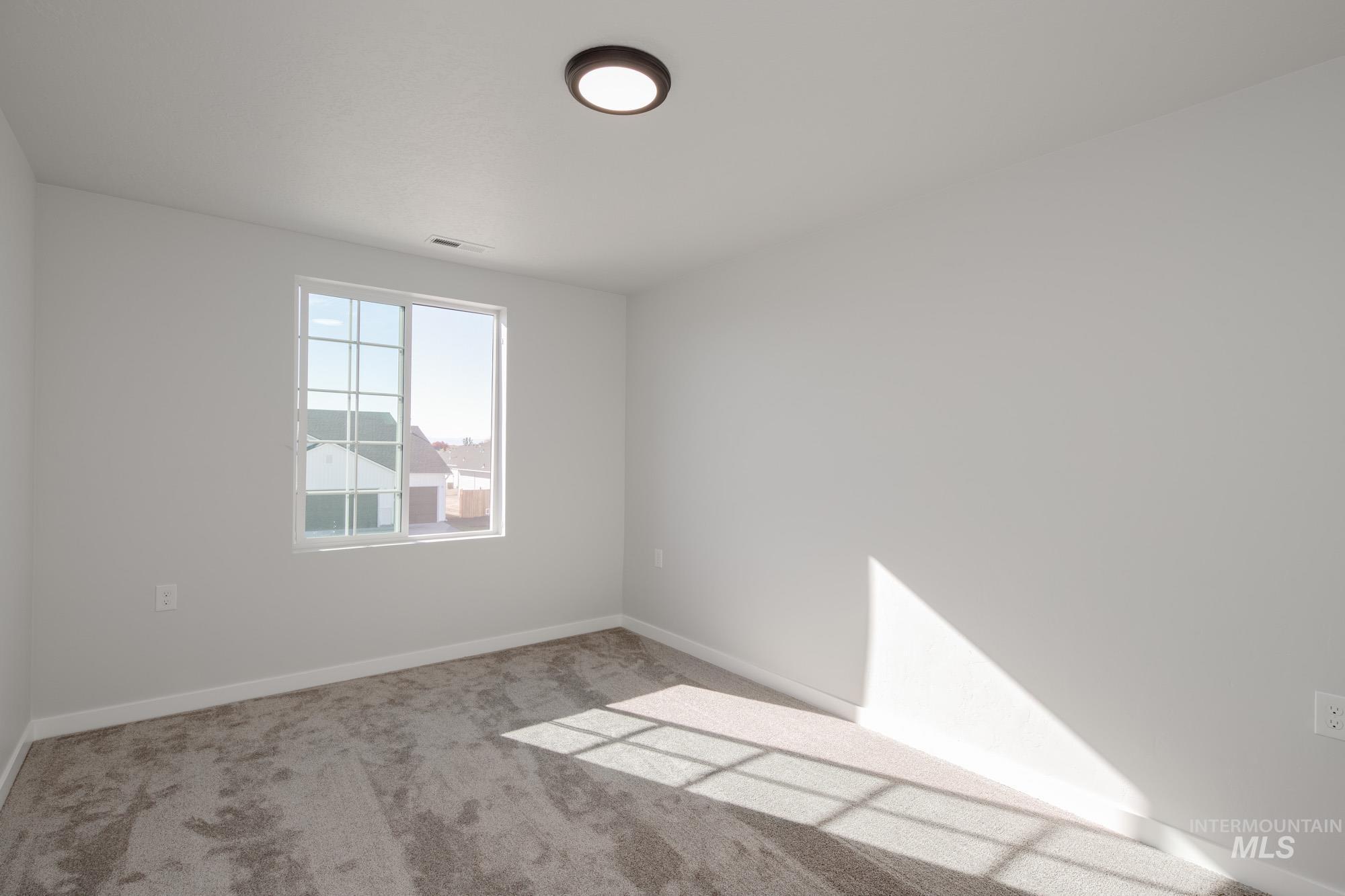 Carpeted spare room featuring baseboards