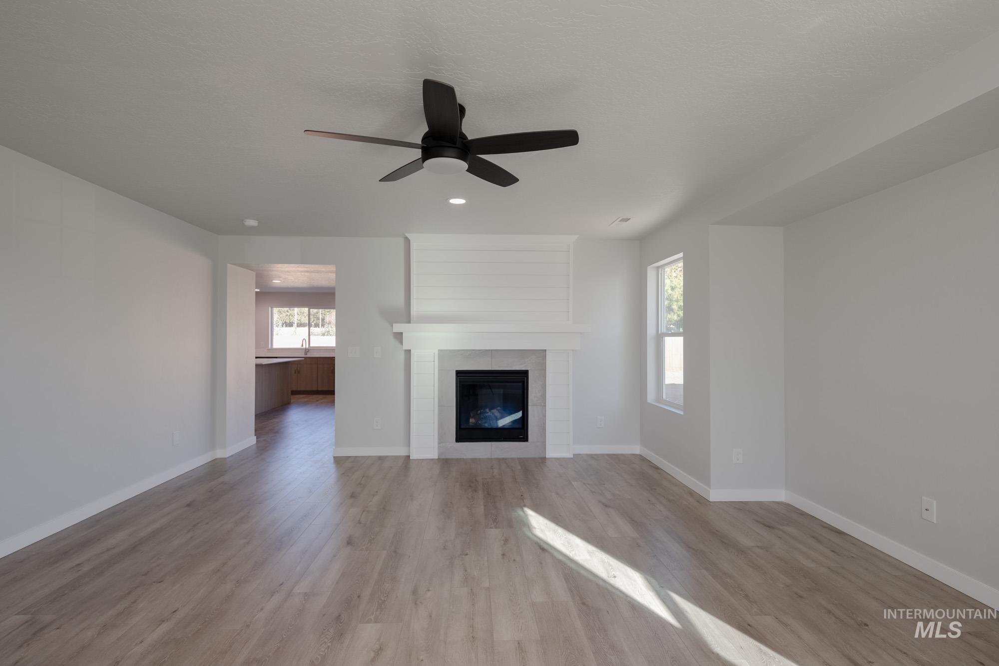 Unfurnished living room featuring a fireplace, light wood-style floors, a ceiling fan, and recessed lighting