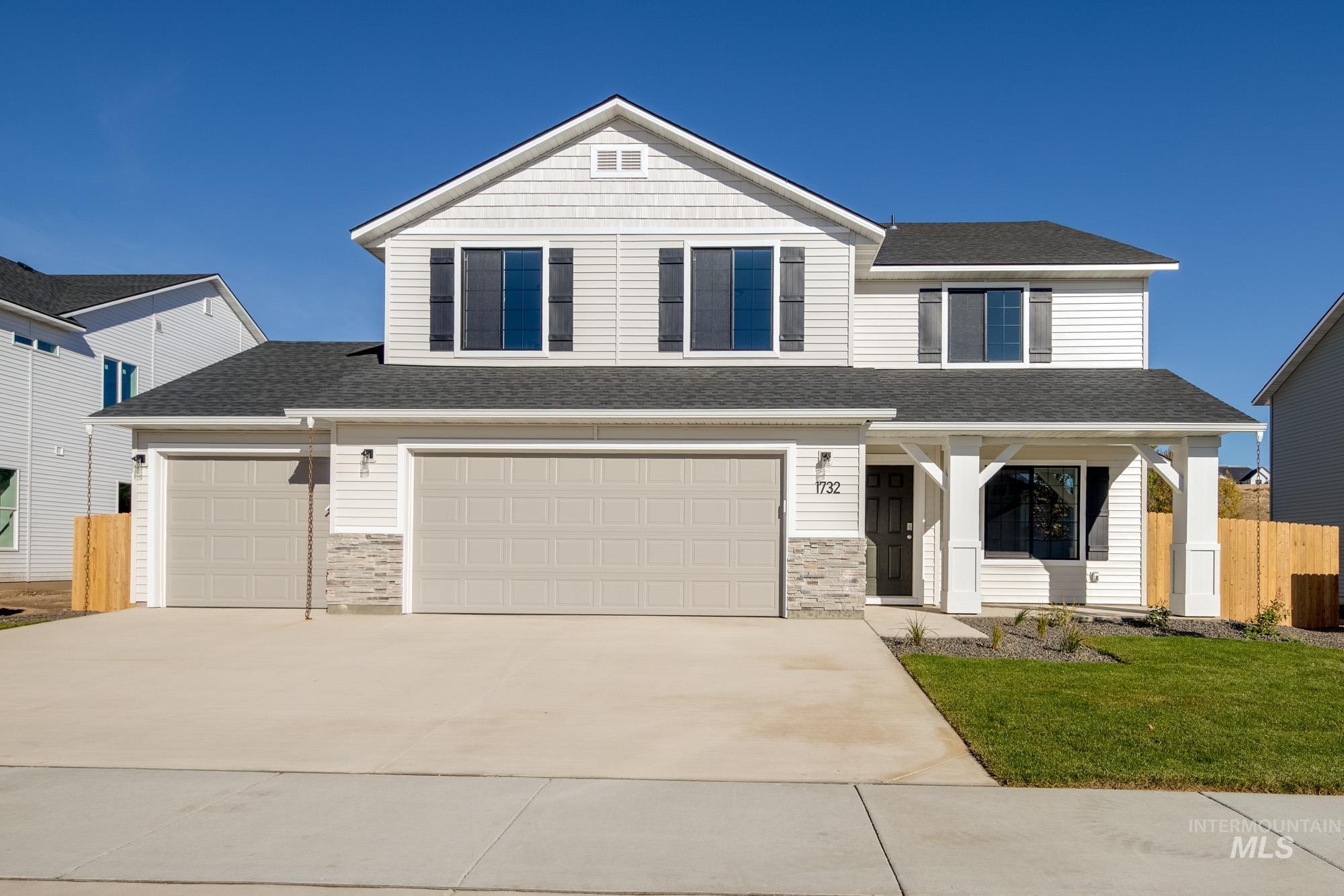 View of front of house with roof with shingles, a porch, concrete driveway, and stone siding