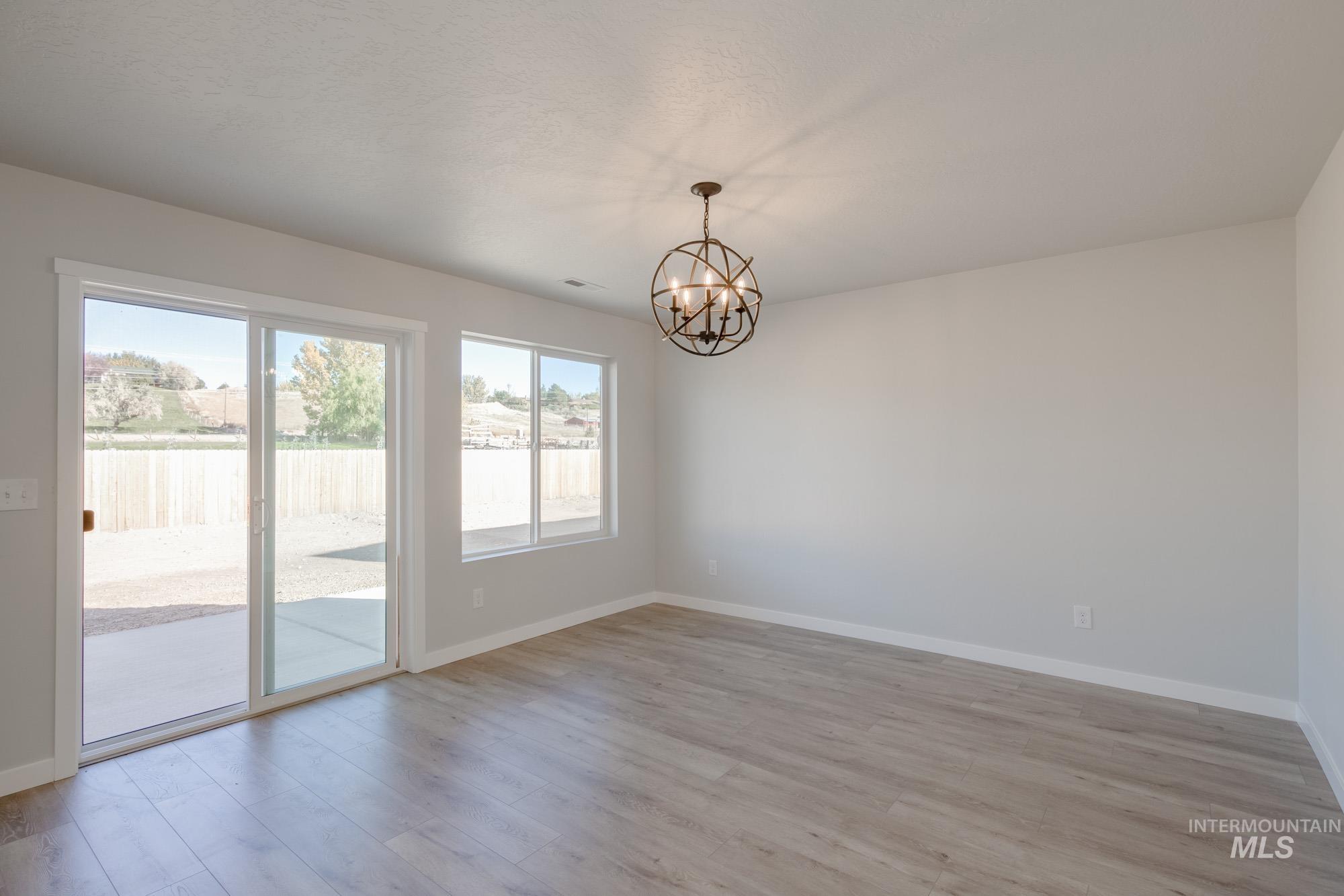 Unfurnished room with light wood-style floors and a chandelier