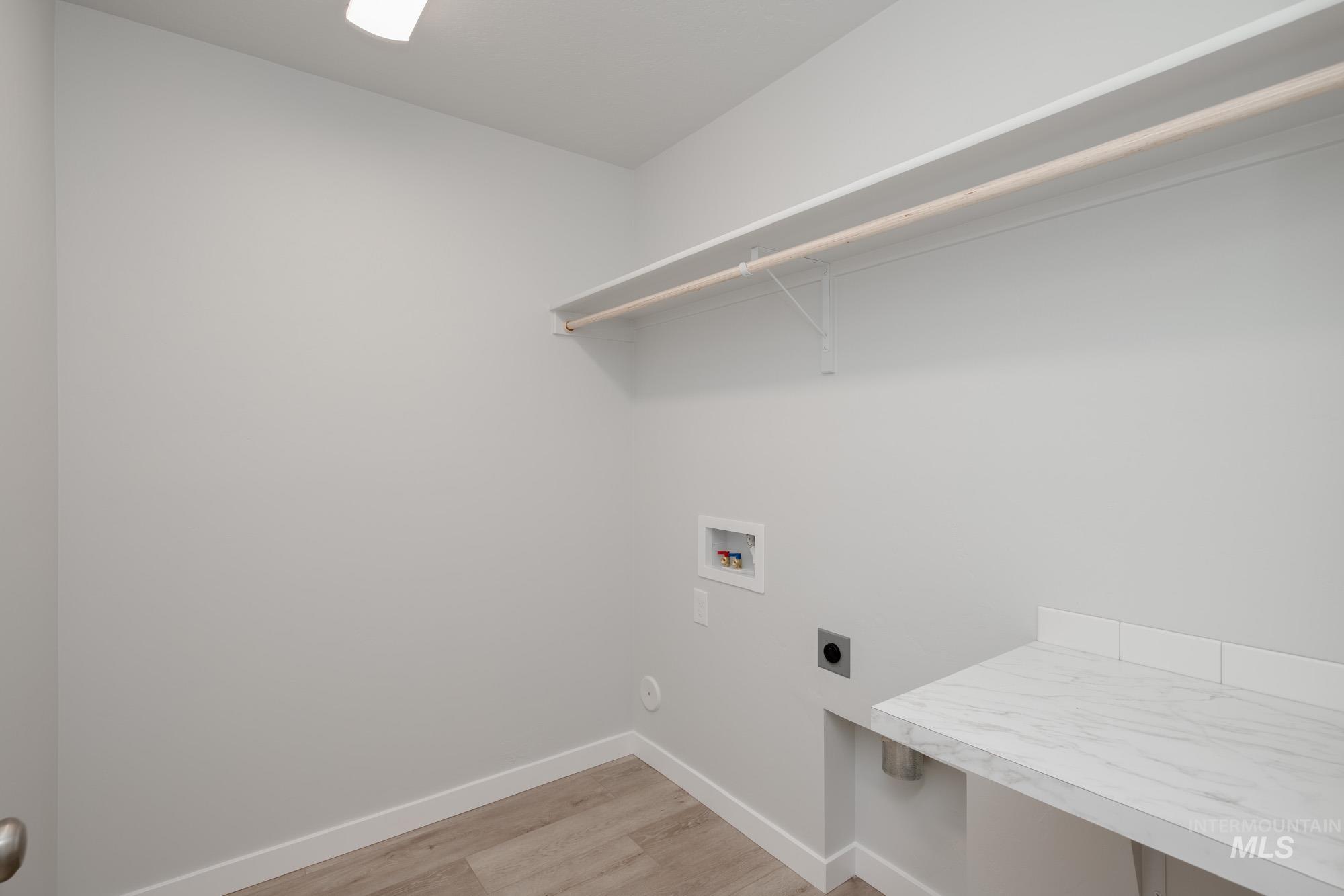 Washroom with light wood-style floors, hookup for an electric dryer, and hookup for a washing machine