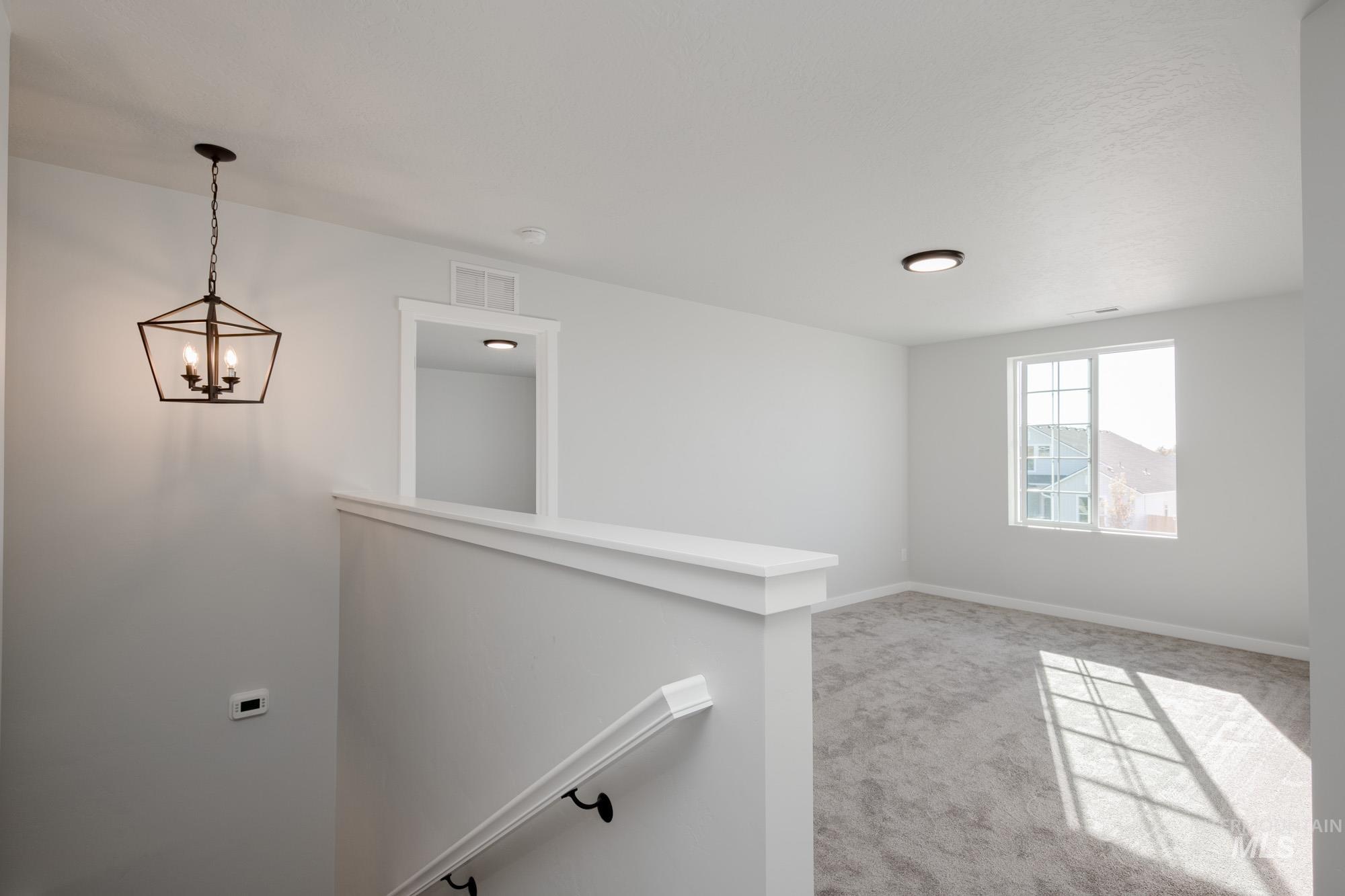 Unfurnished room with light colored carpet and a chandelier