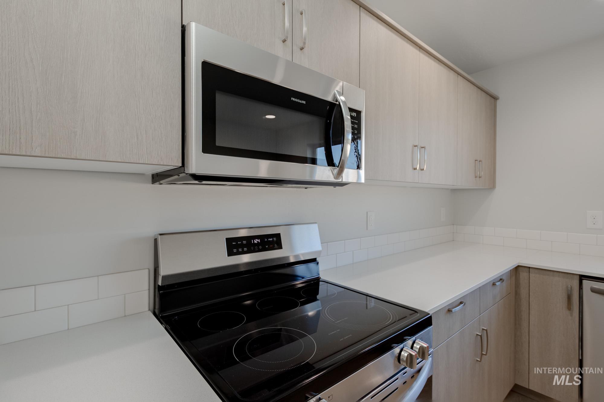 Kitchen with light brown cabinetry, stainless steel appliances, and modern cabinets