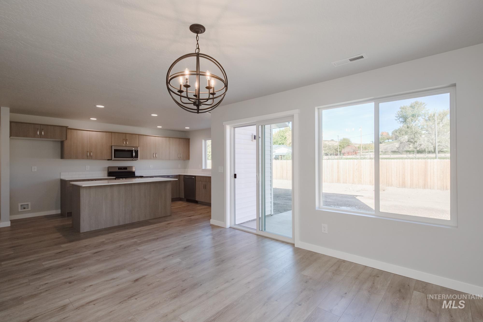 Kitchen featuring a kitchen island, hanging light fixtures, recessed lighting, light countertops, and open floor plan