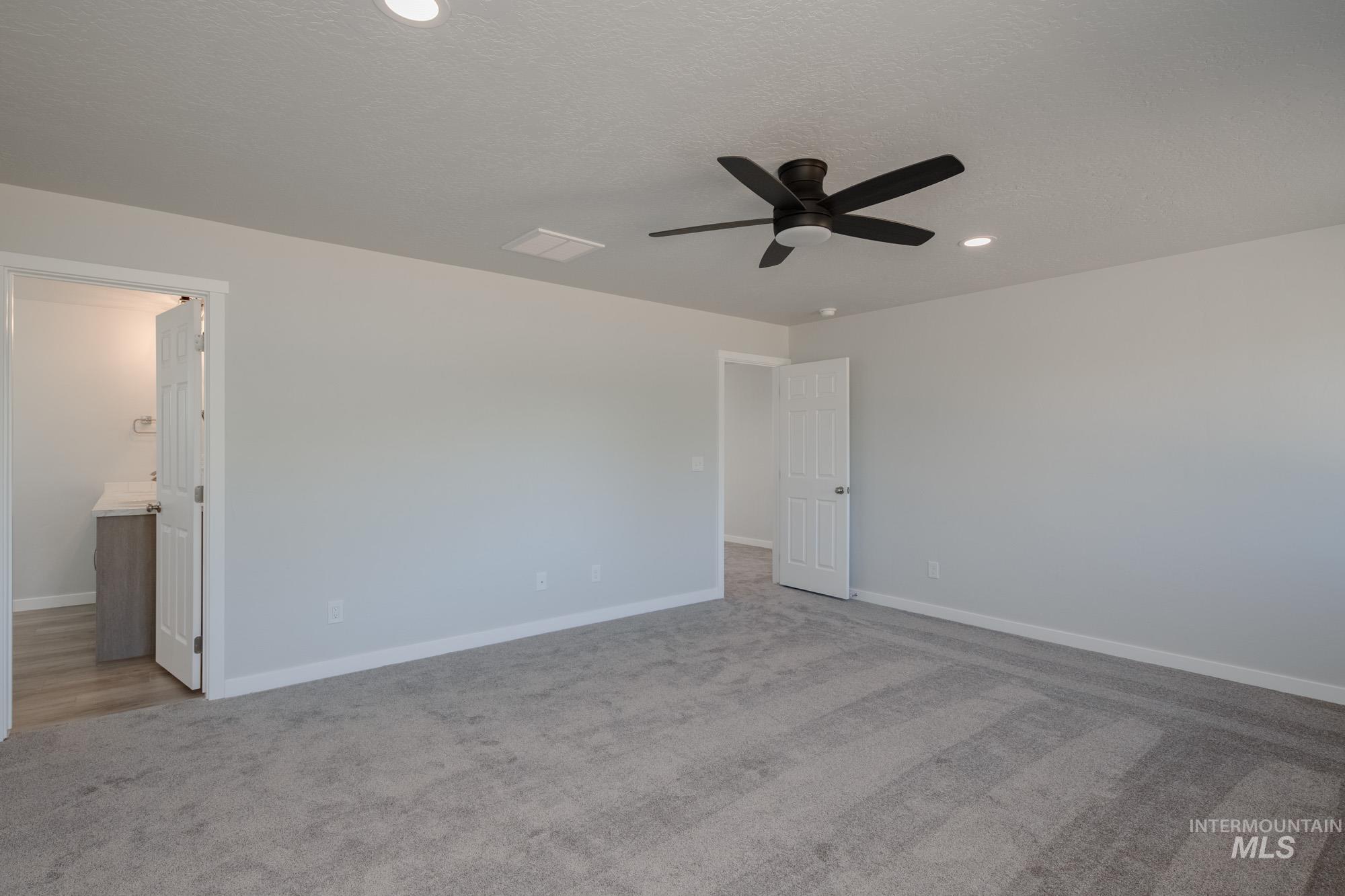Unfurnished bedroom featuring light carpet, a ceiling fan, recessed lighting, ensuite bath, and a textured ceiling