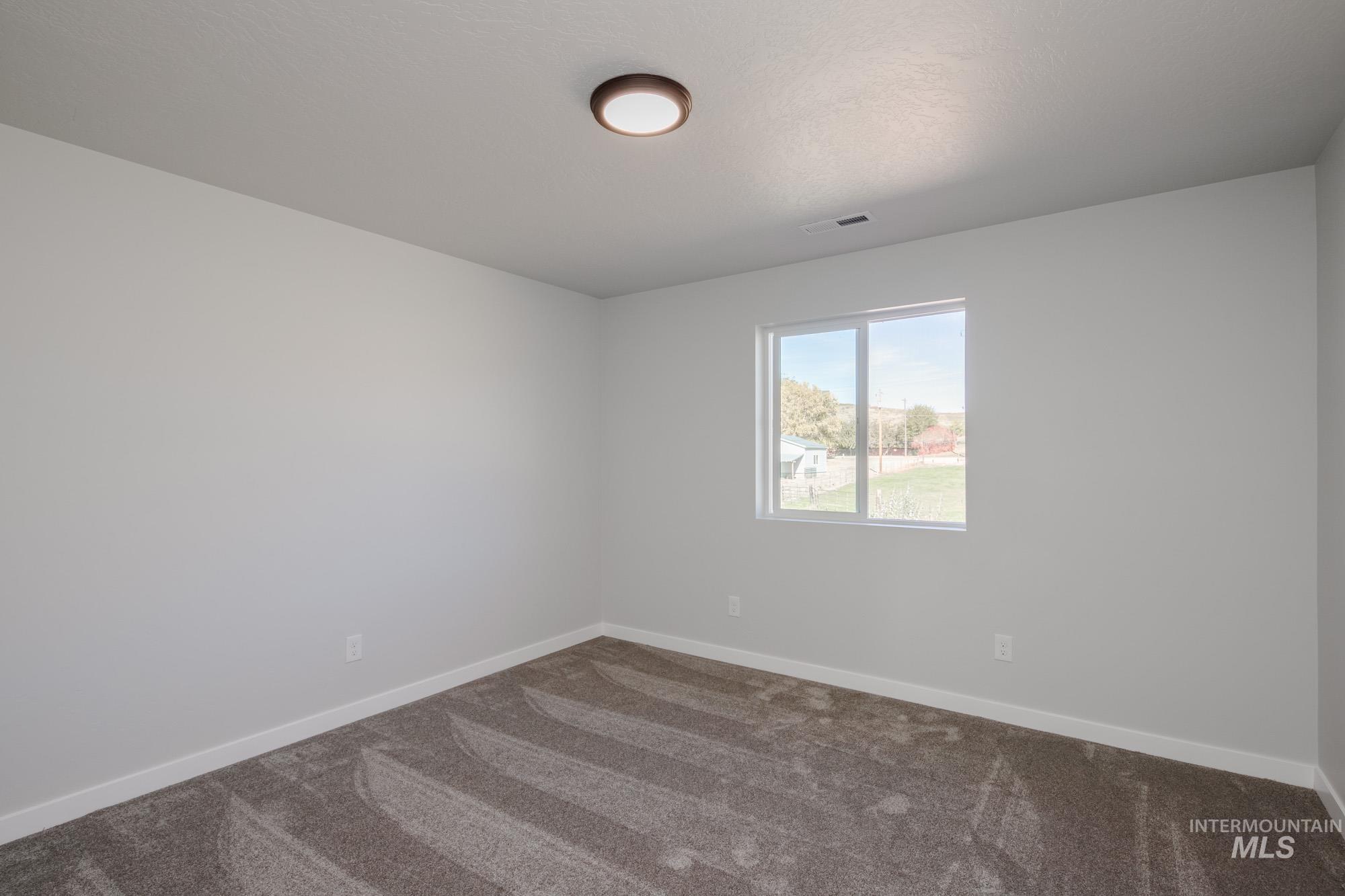 Carpeted spare room with baseboards