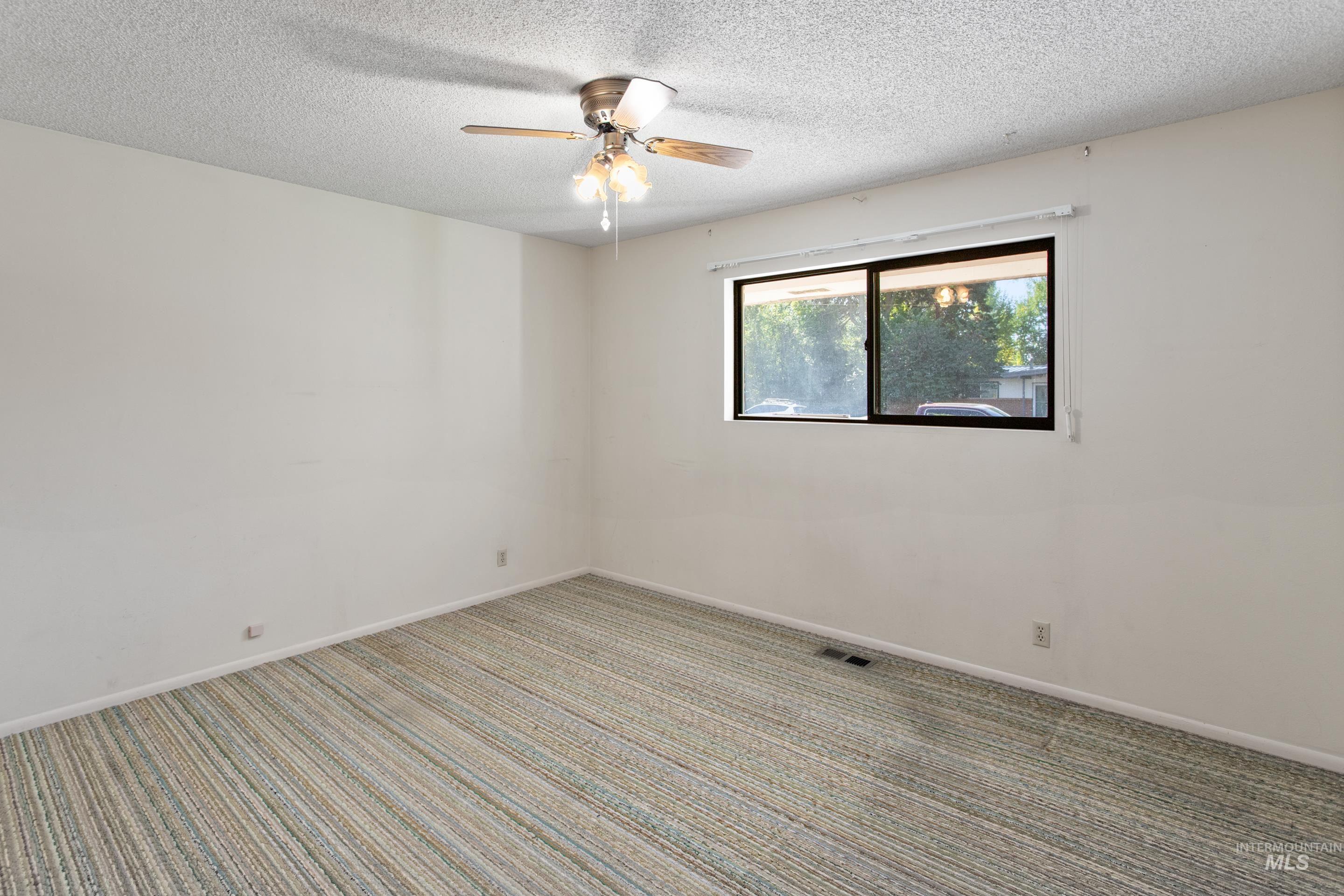 Carpeted spare room featuring a textured ceiling and ceiling fan