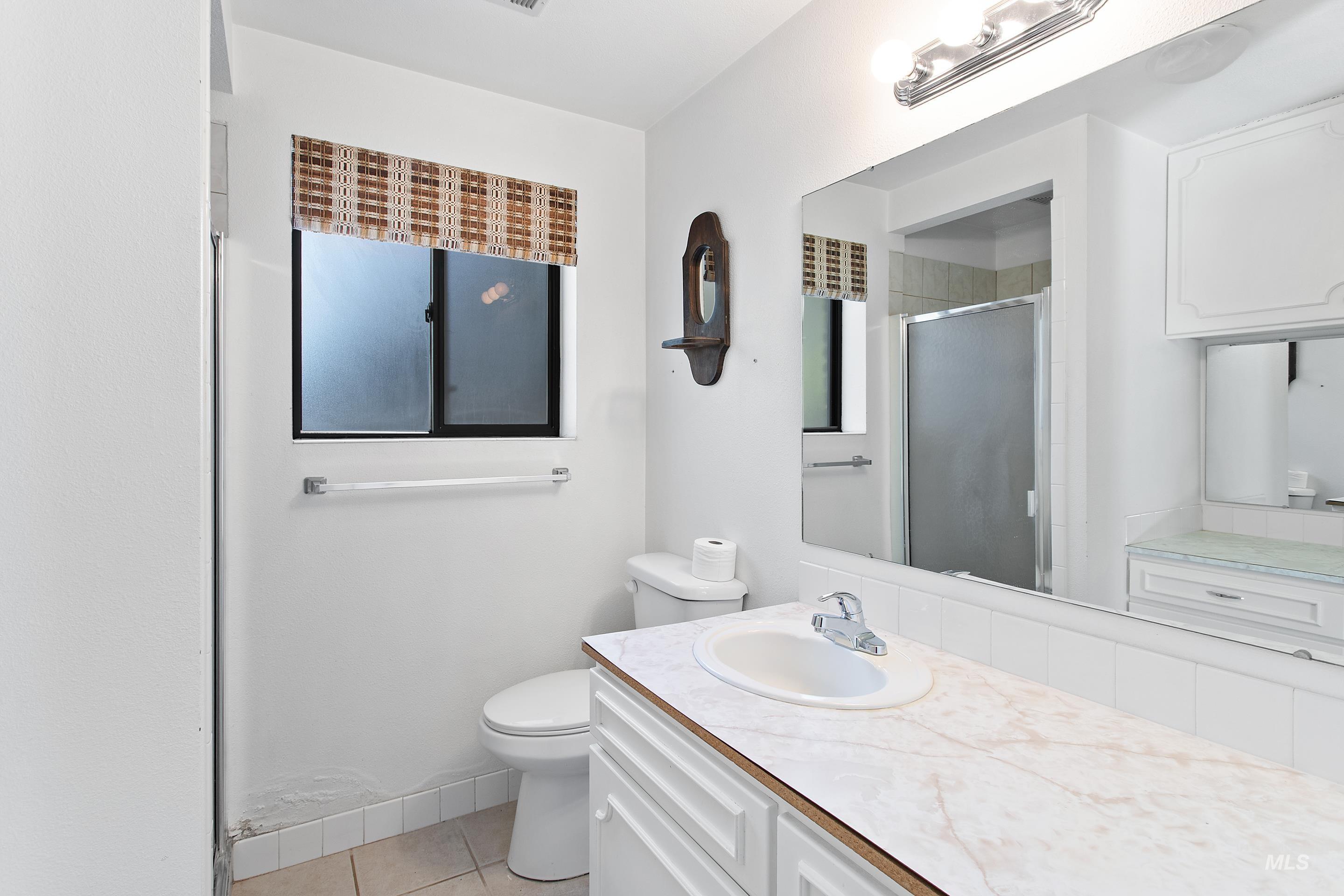 Full bath with a stall shower, vanity, and light tile patterned flooring