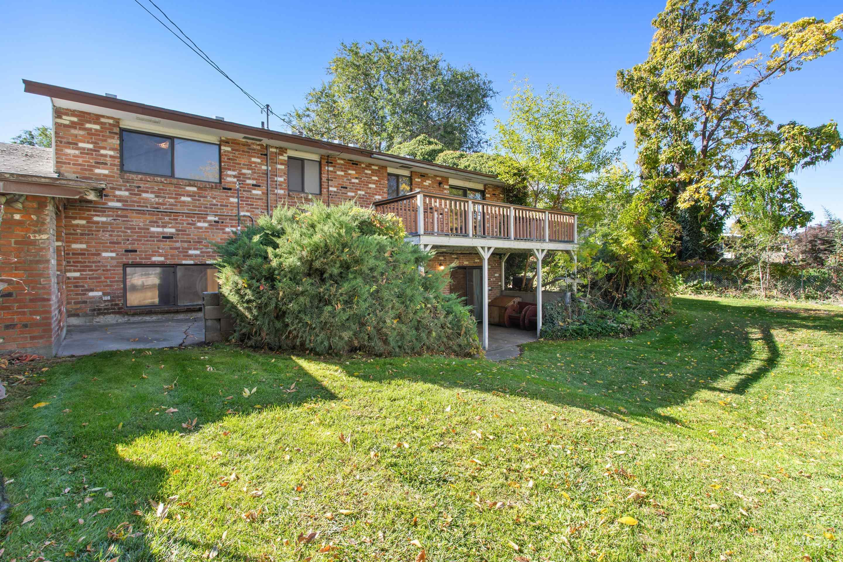 Back of house with a patio, brick siding, a yard, and a wooden deck