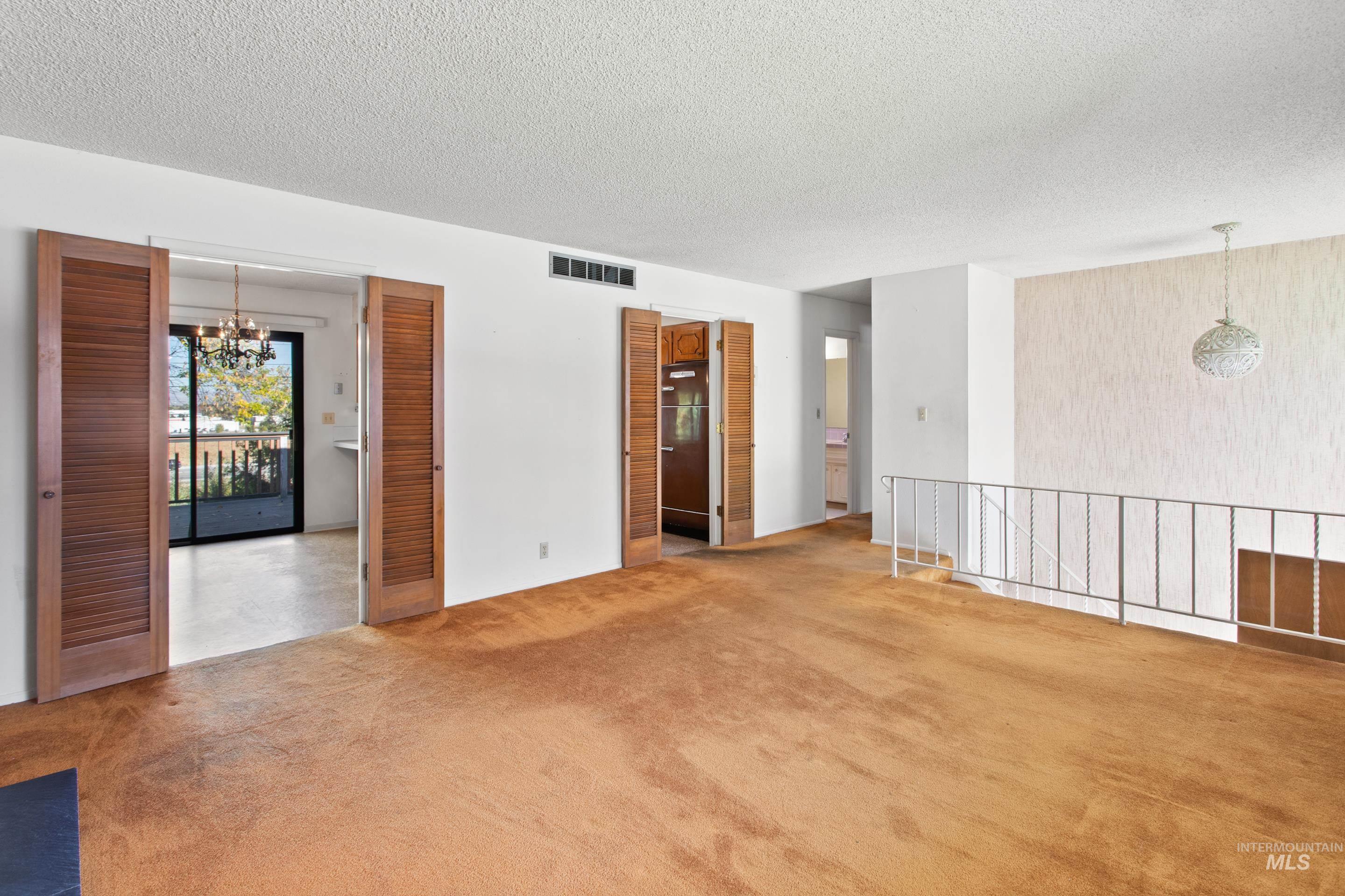 Unfurnished room featuring a chandelier, carpet flooring, and a textured ceiling