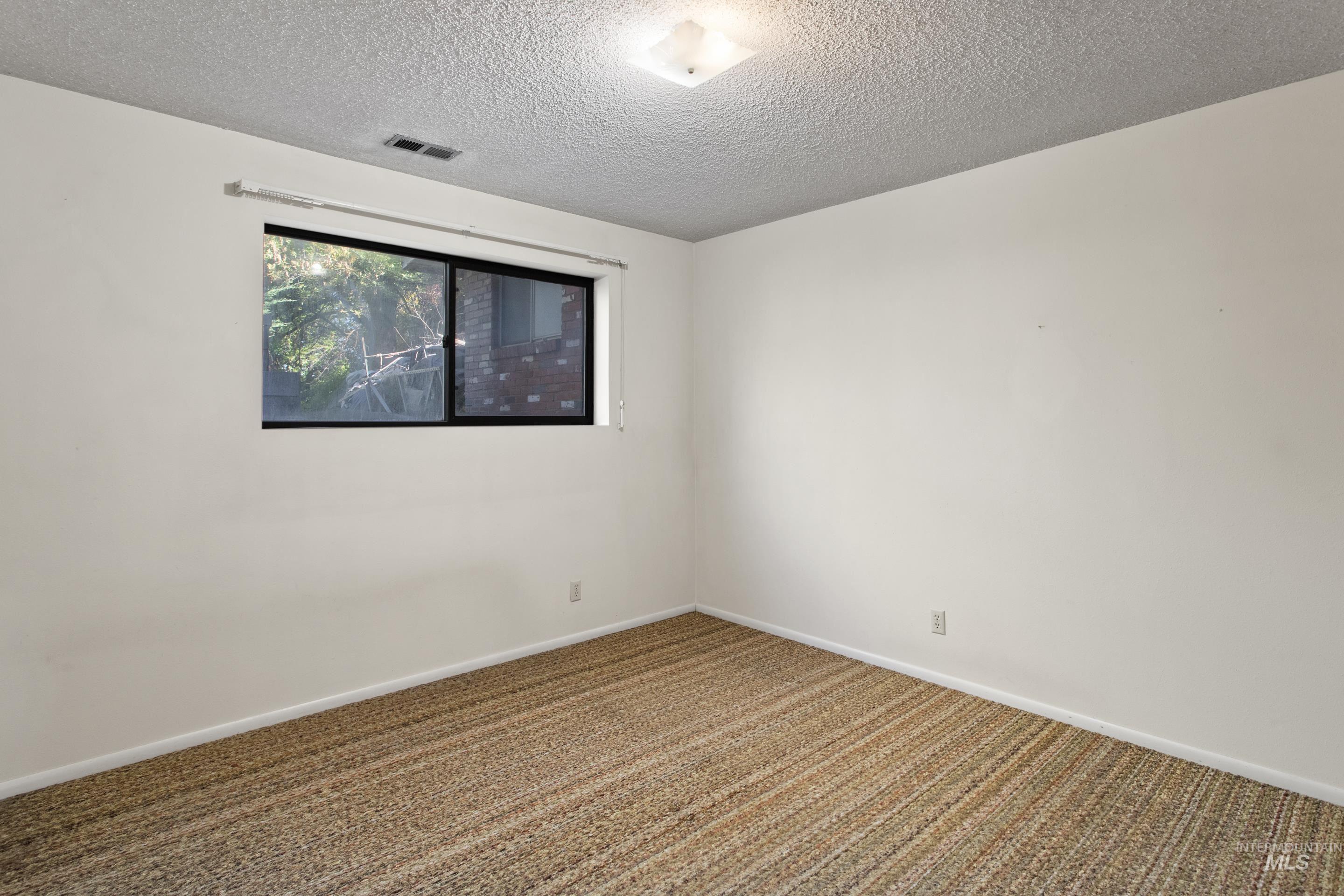 Unfurnished room featuring carpet floors and a textured ceiling