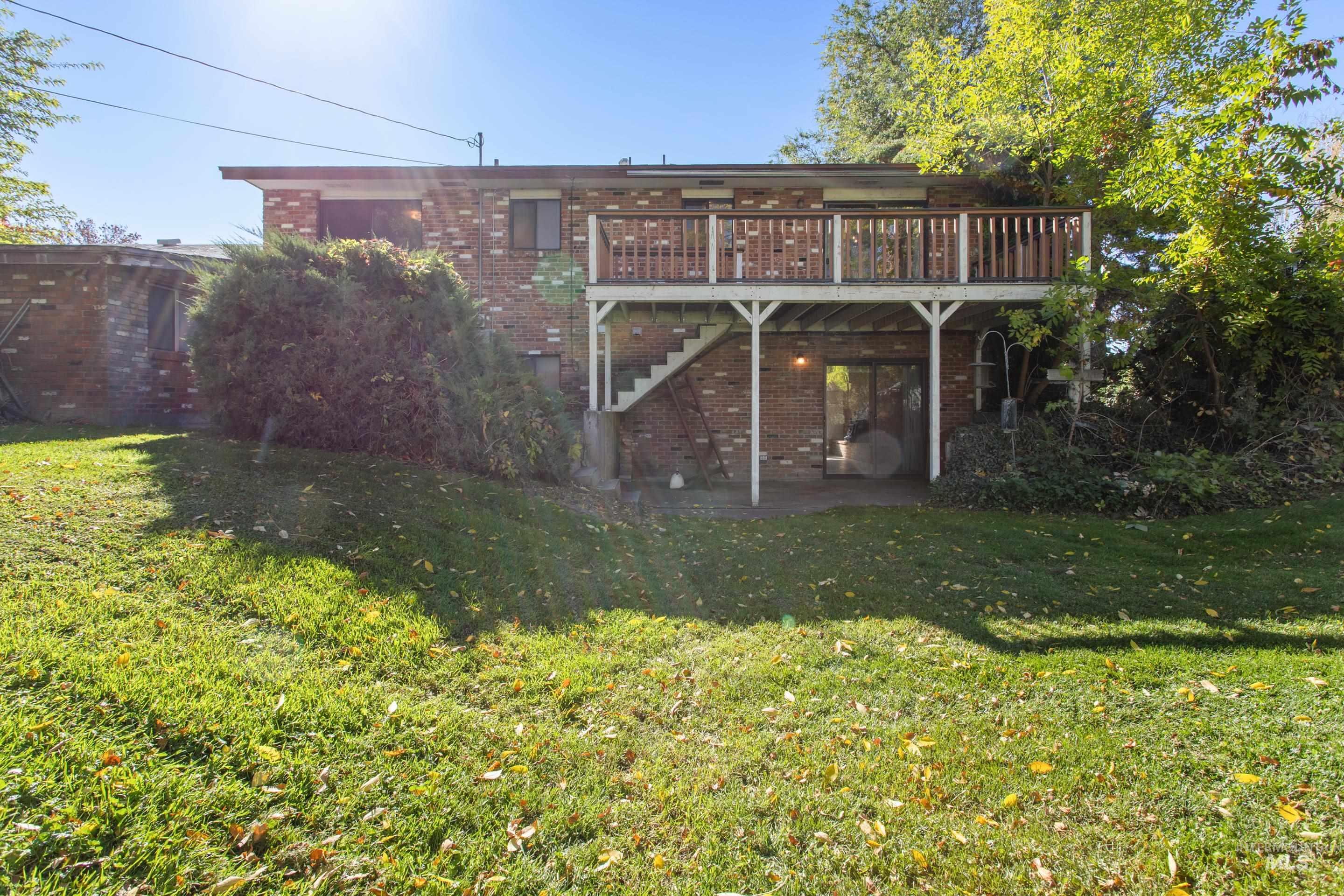Back of house featuring a patio area, brick siding, a yard, and a deck
