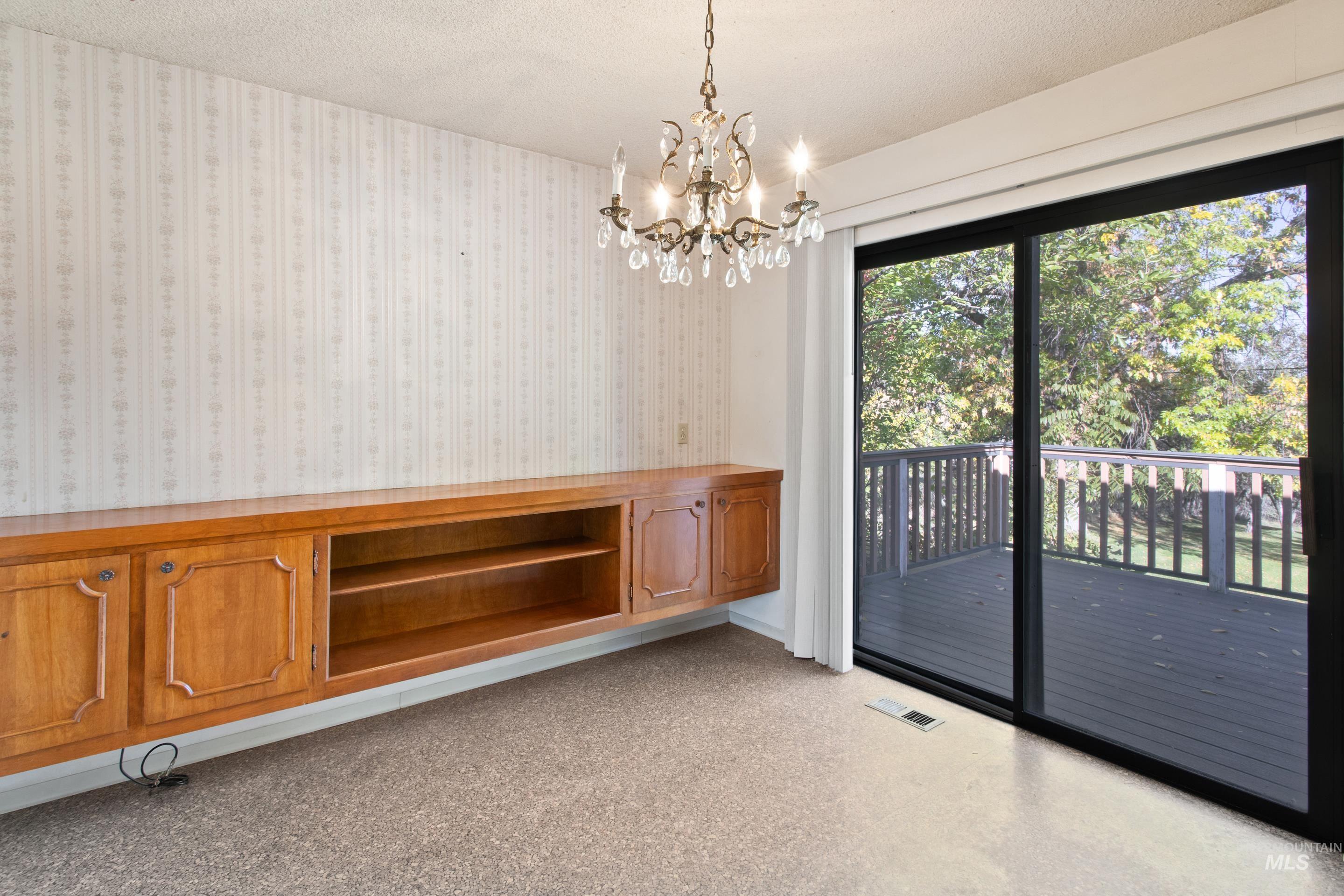 Unfurnished dining area with a textured ceiling and a chandelier