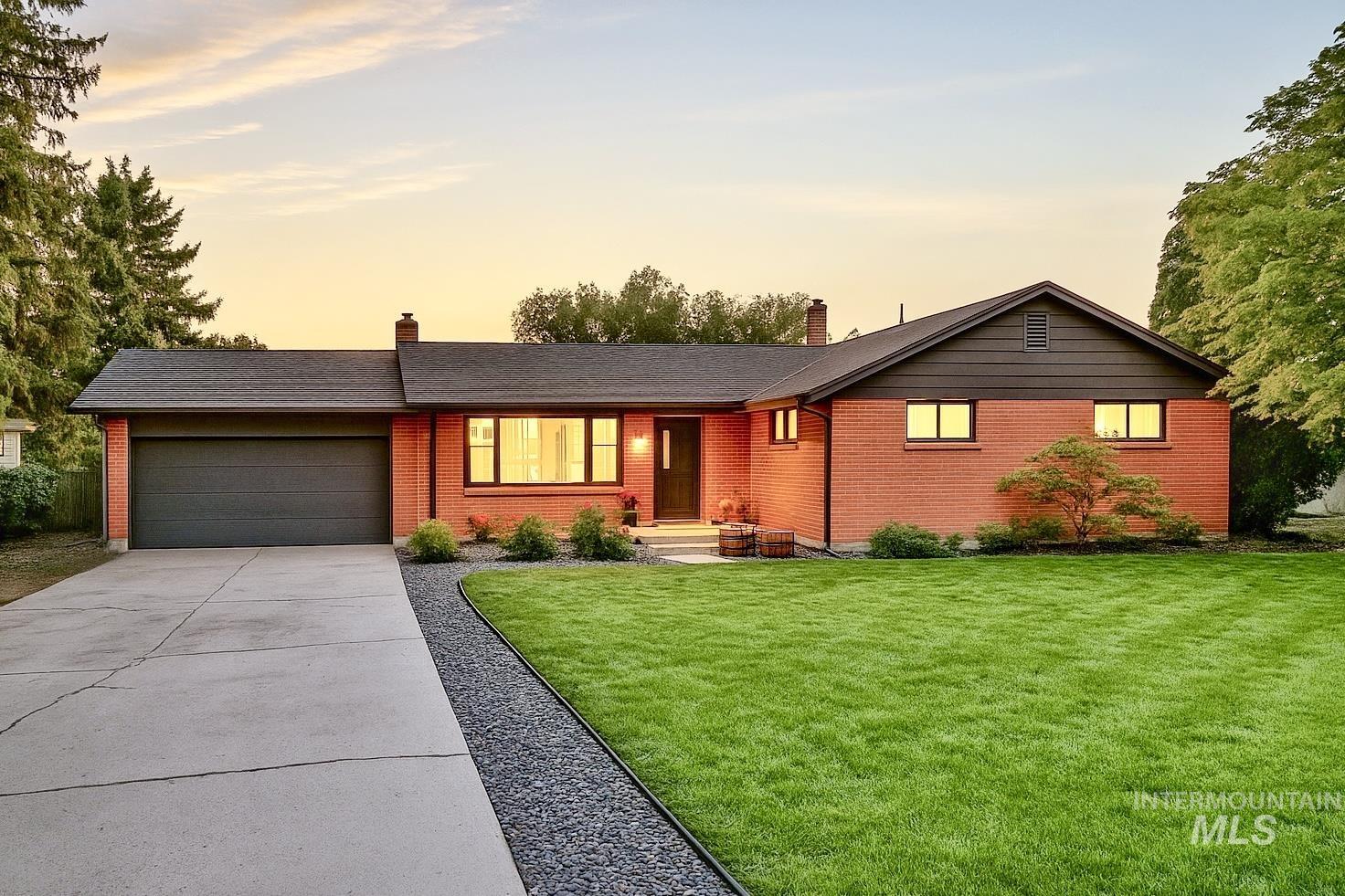 Ranch-style house featuring a chimney, a front yard, concrete driveway, and brick siding