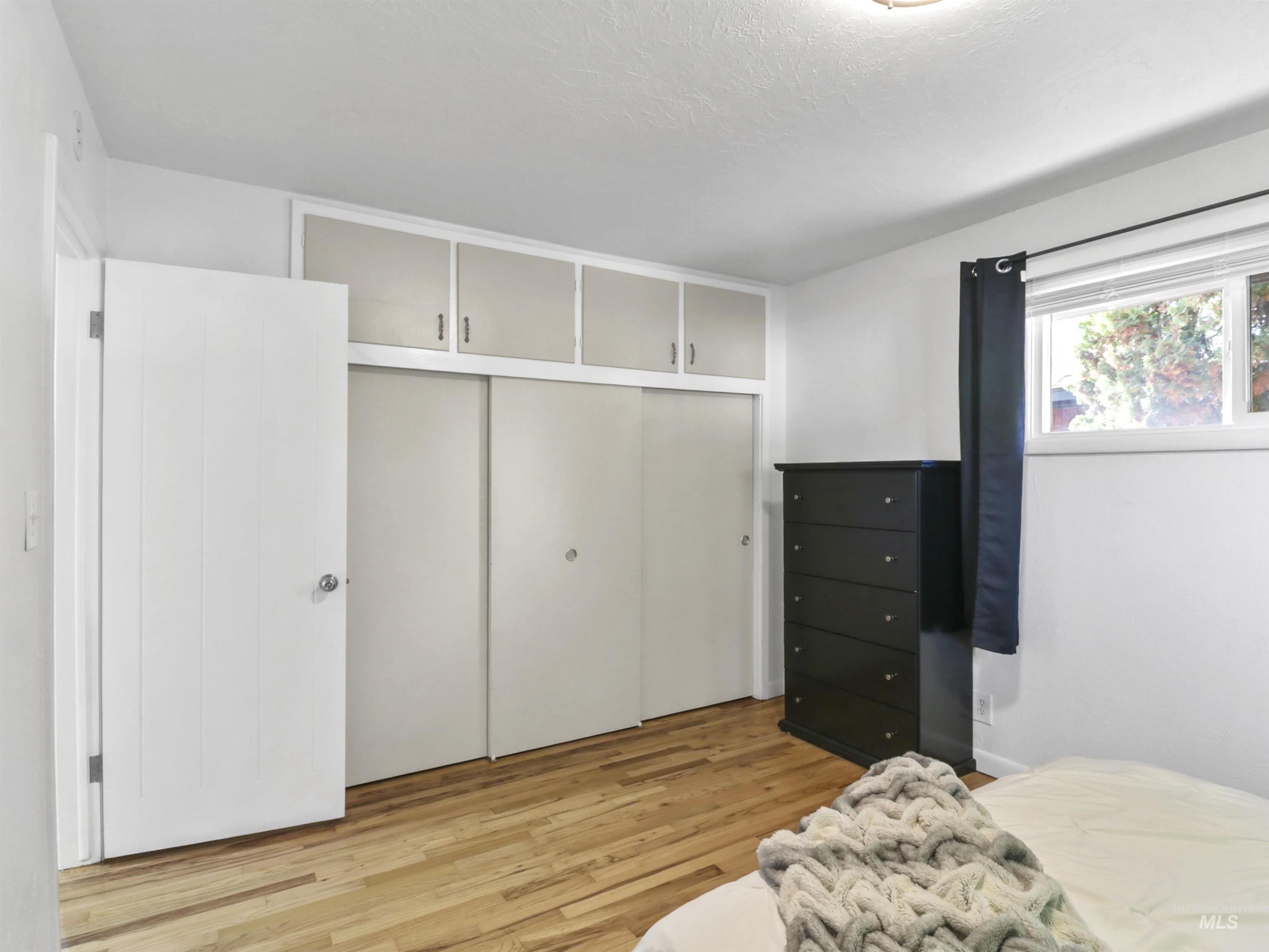 Bedroom with a closet, light wood finished floors, and a textured ceiling