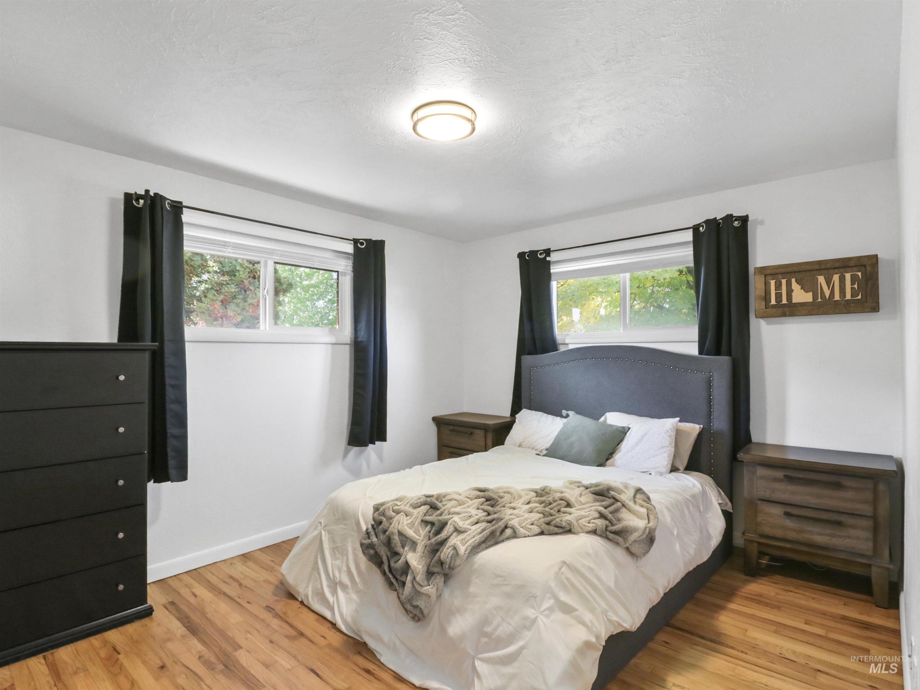 Bedroom with multiple windows, light wood-style flooring, and a textured ceiling